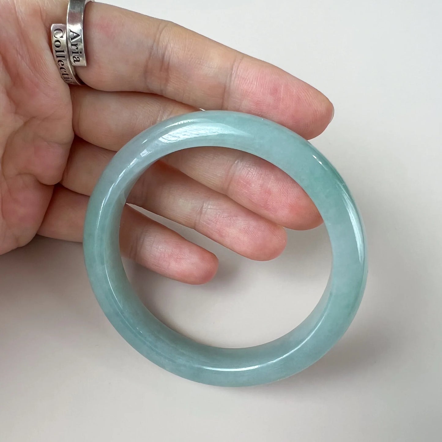 Handheld view of translucent jade bangle with high-gloss finish and rounded profile