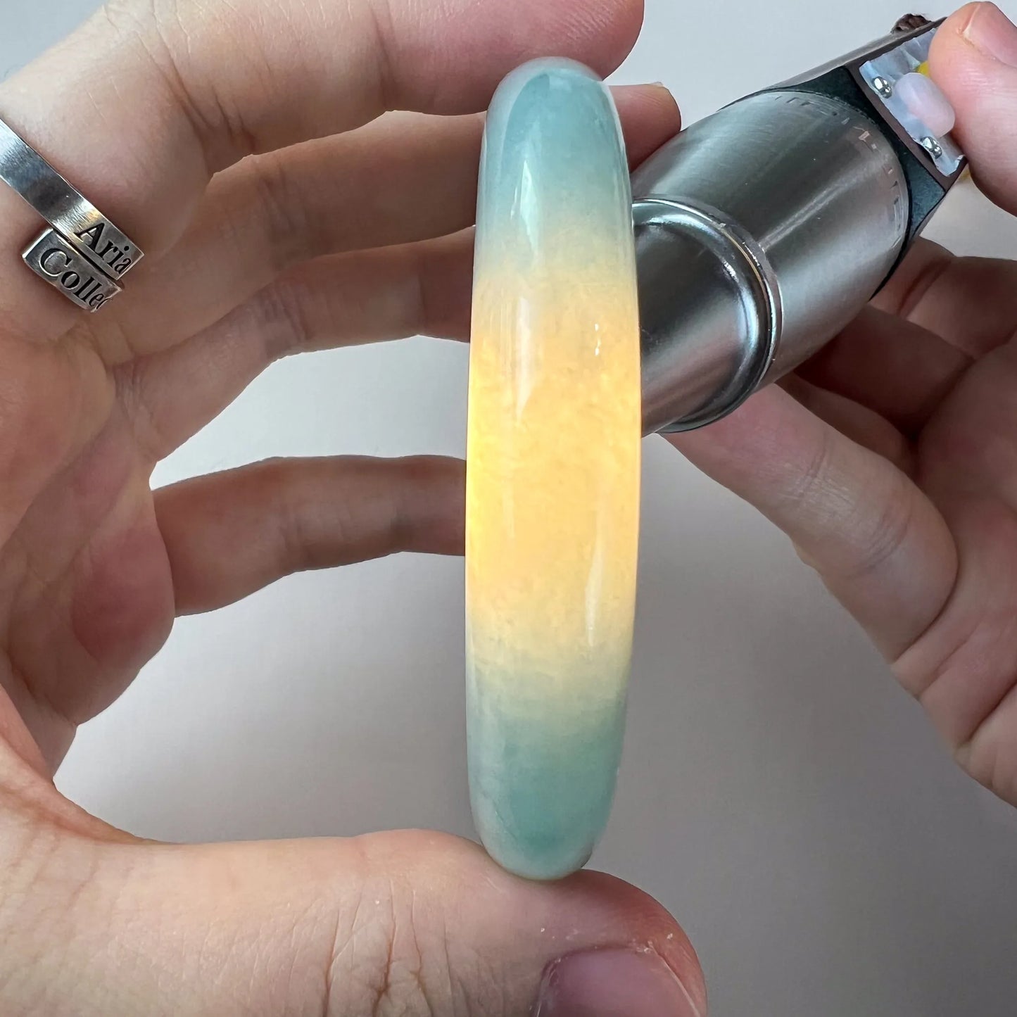 Side profile of polished jade bangle showing translucent green and yellow color variation