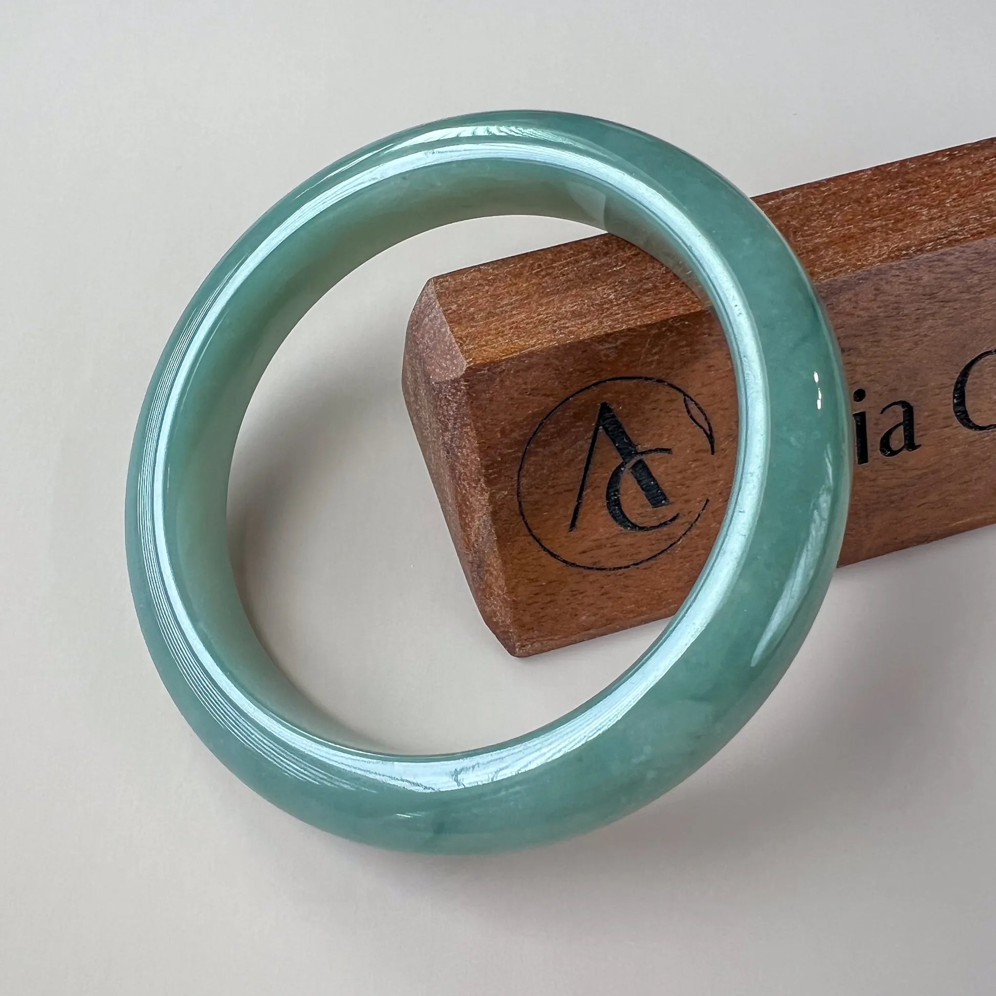 Front-facing polished green jade bangle on display stand, glossy finish