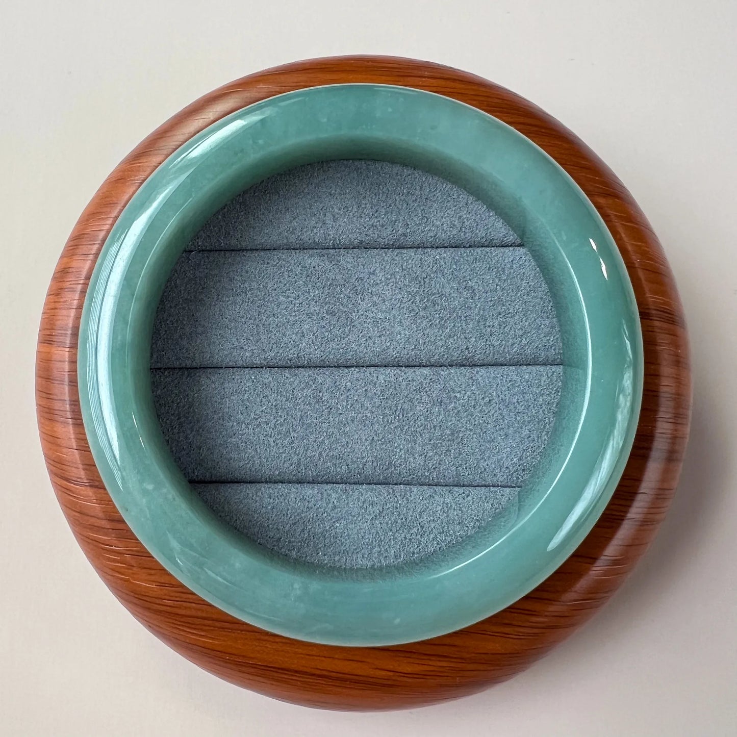 Top view of polished jade bangle resting on padded wooden stand