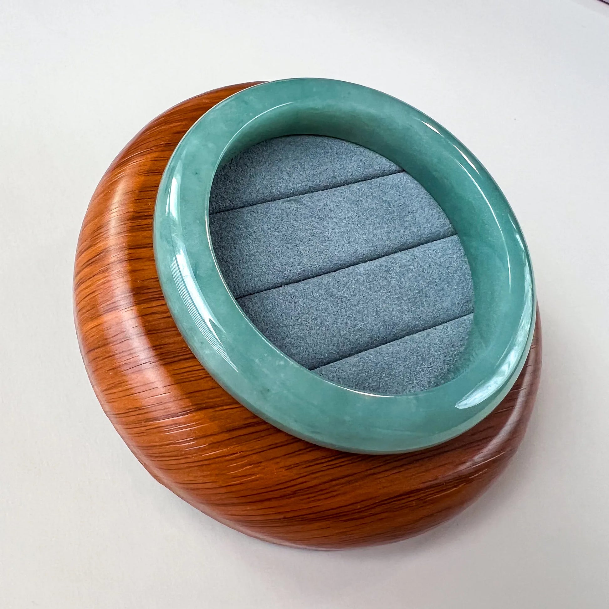 Angled view of green jade bangle on round wooden display base
