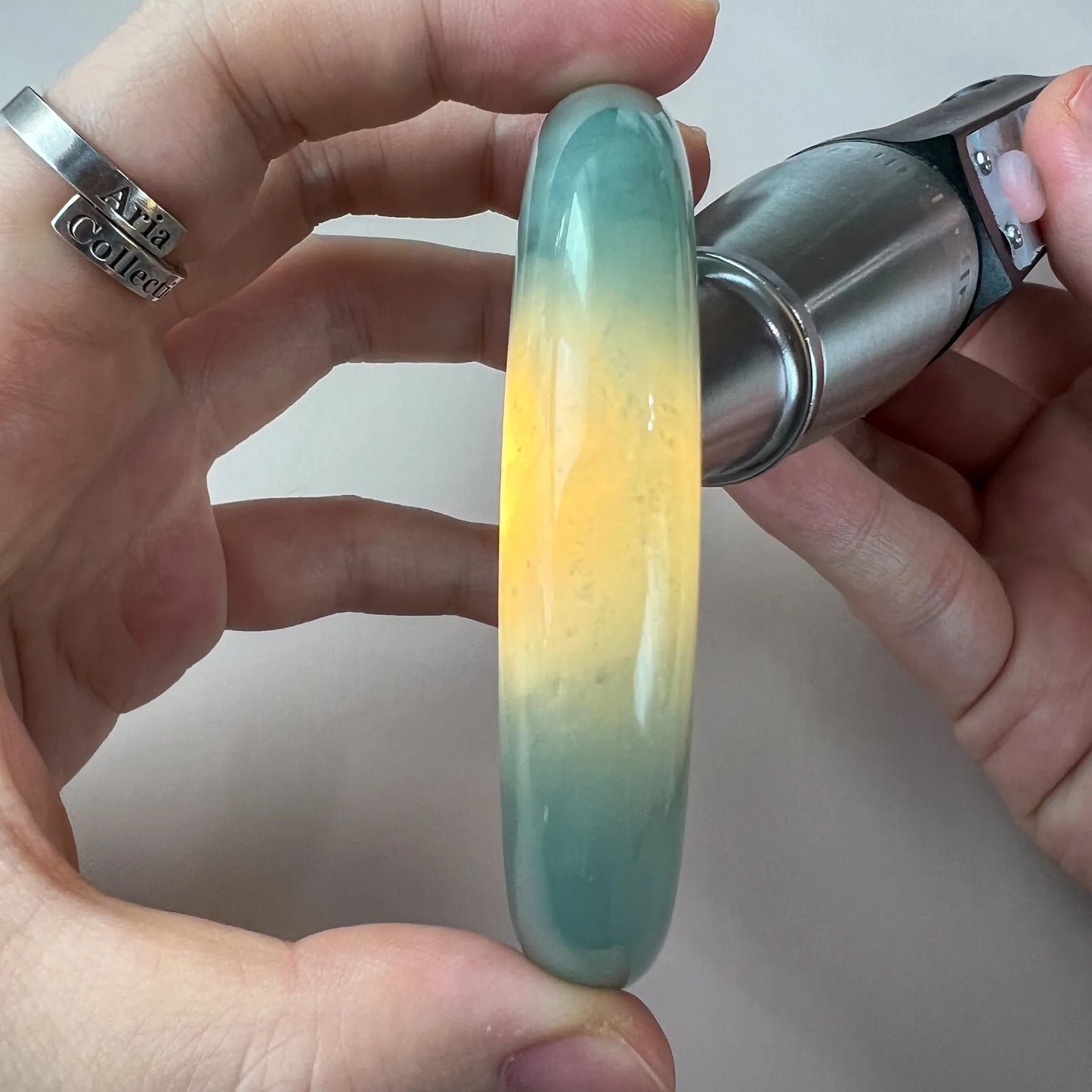 Backlit side view of jade bangle showing translucent green and yellow tones