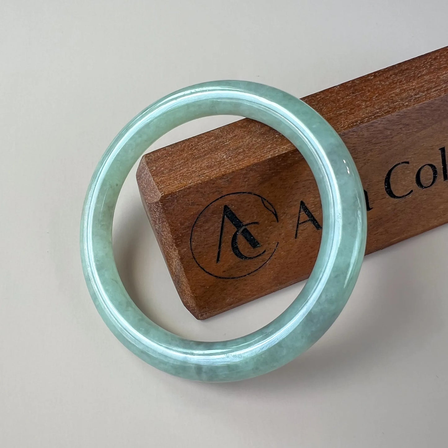 Front view of polished pale green jade bangle on display block