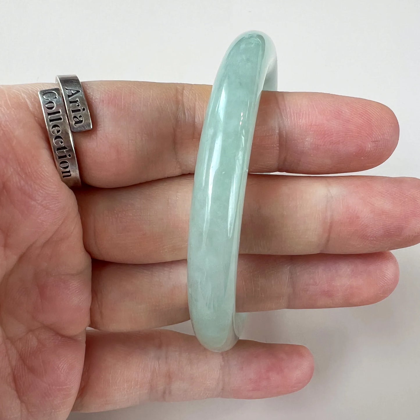 Profile view of smooth light green jade bangle with glossy finish