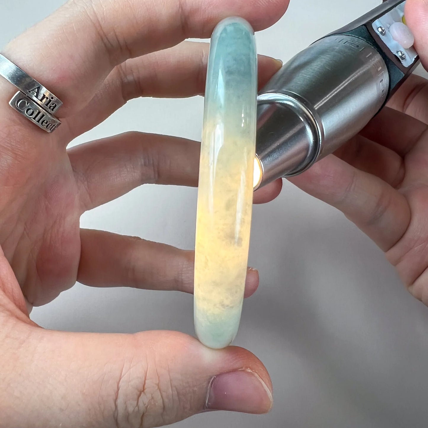 Backlit side view of translucent jade bangle showing natural color variation