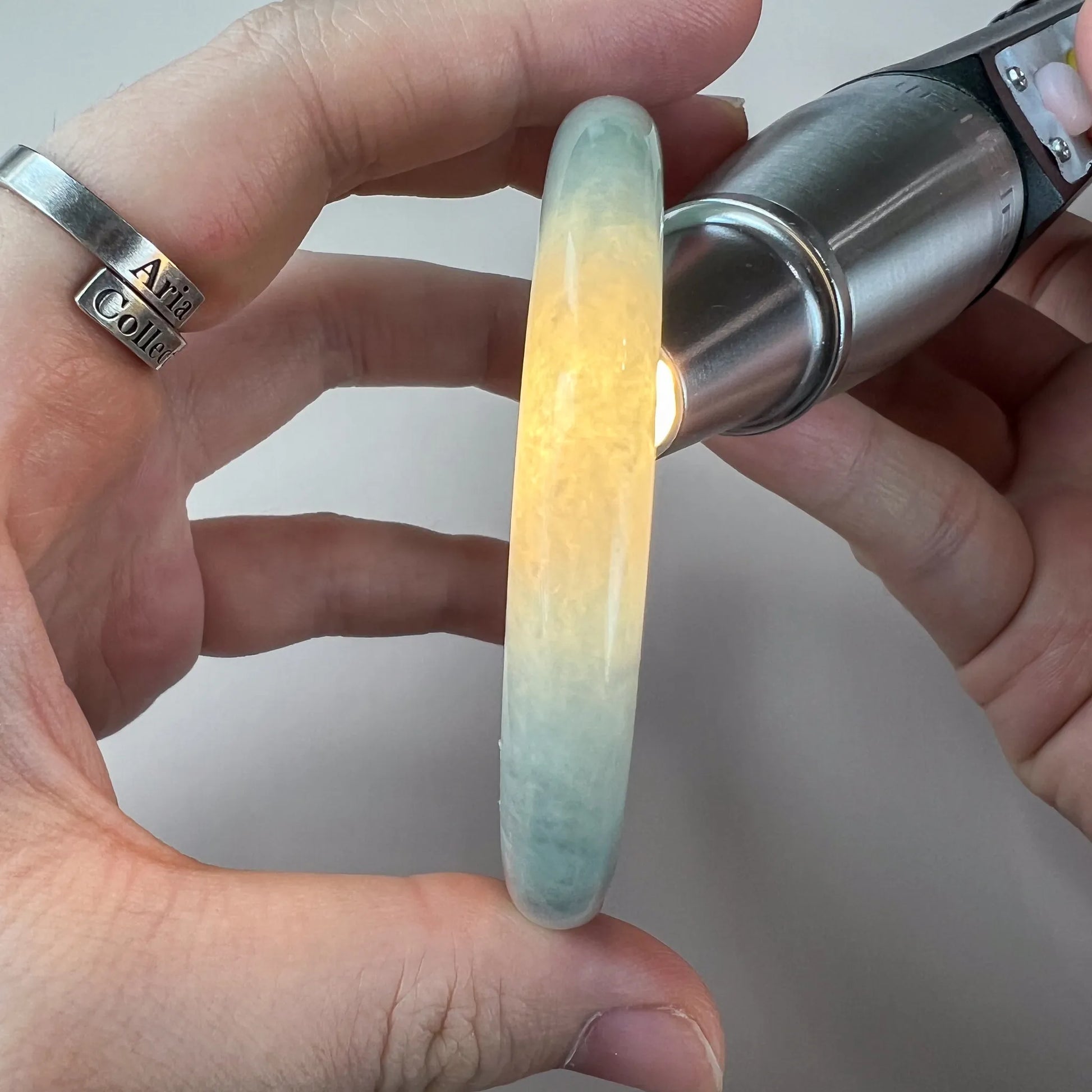 Backlit side view of pale green jade bangle with warm yellow translucency