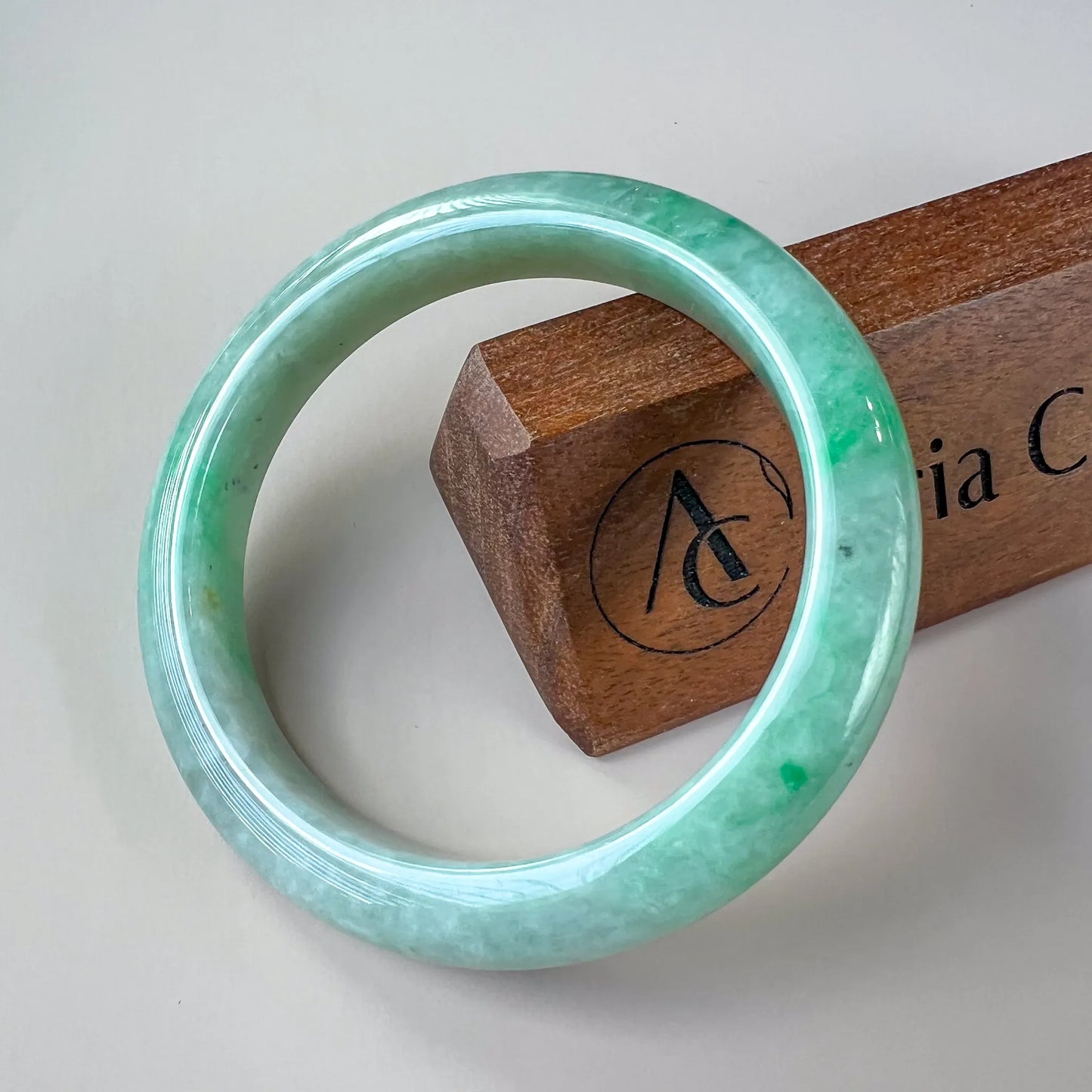 Front view of polished green jade bangle with smooth rounded profile on white background