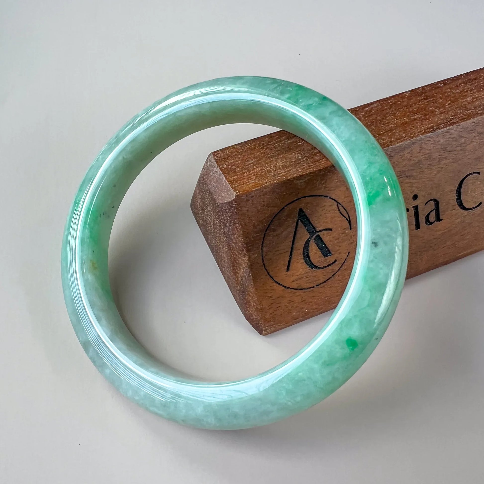 Front view of polished green jade bangle with smooth rounded profile on white background