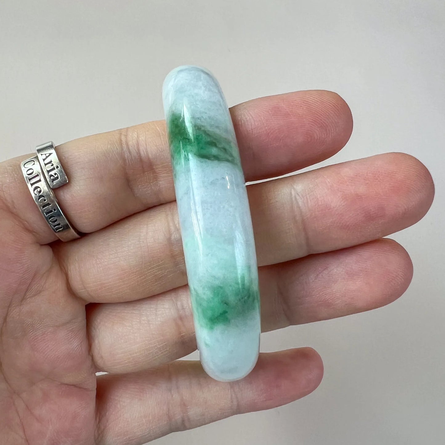 Side profile of slim jade bangle showing rounded polished edge and green inclusions