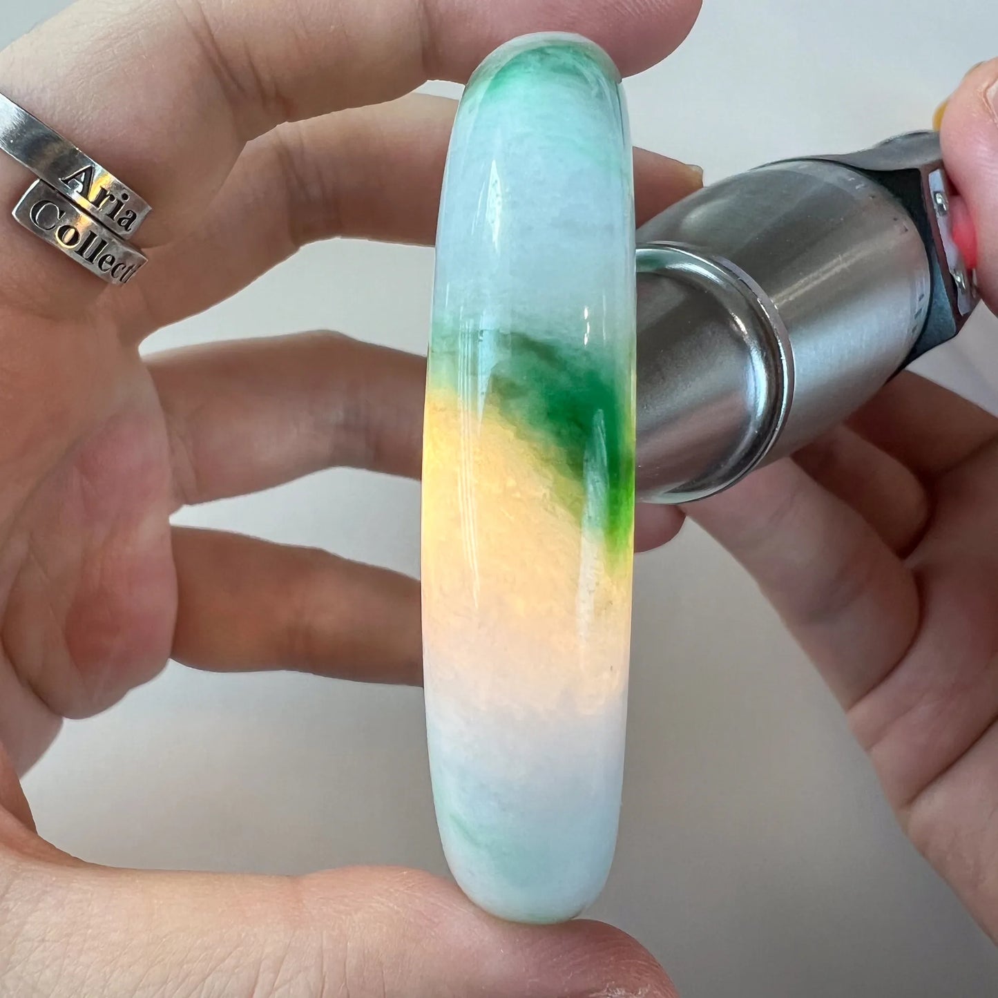 Side view of jade bangle under backlight, revealing translucent yellow-green color band