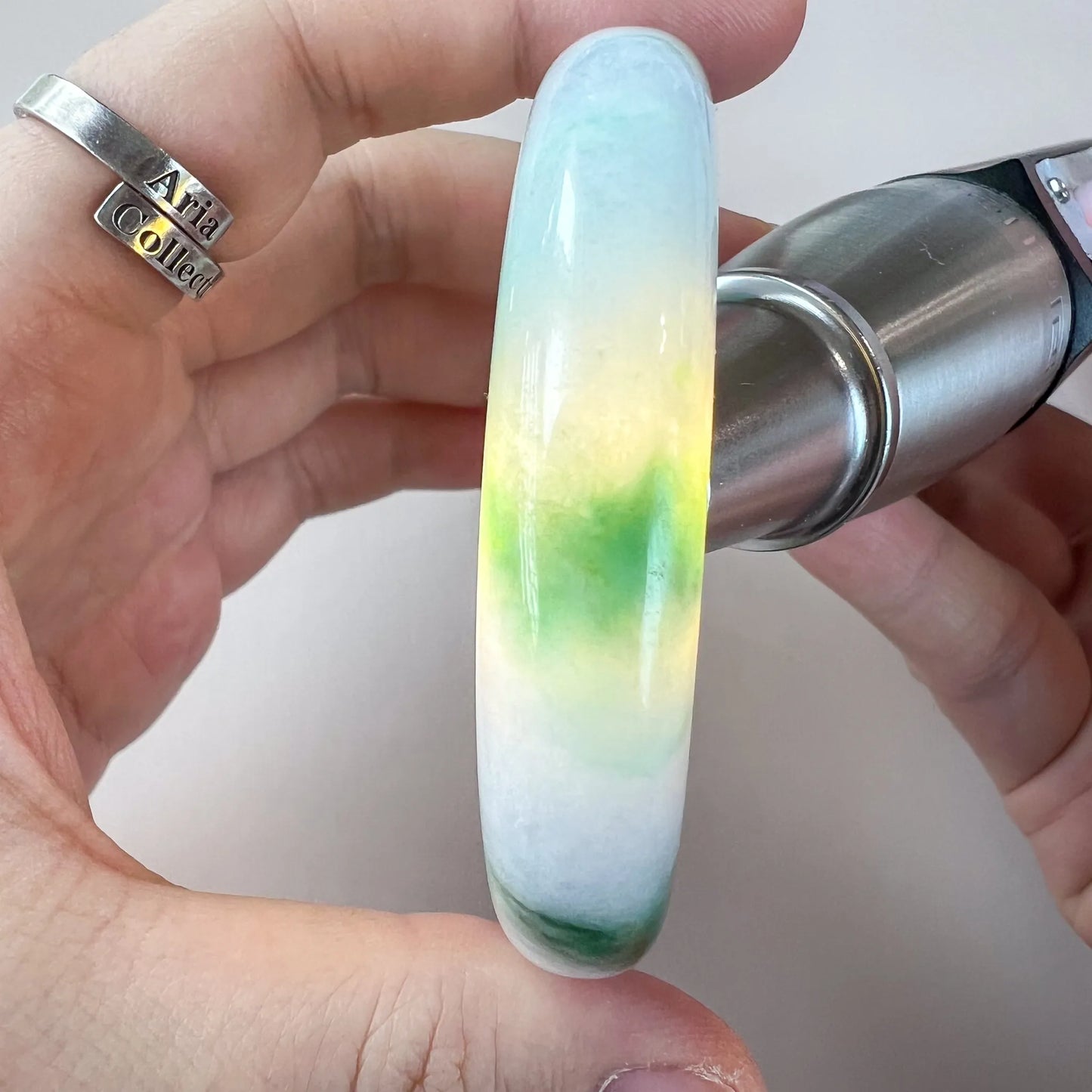 Side view of translucent jade bangle with soft green center and glossy finish