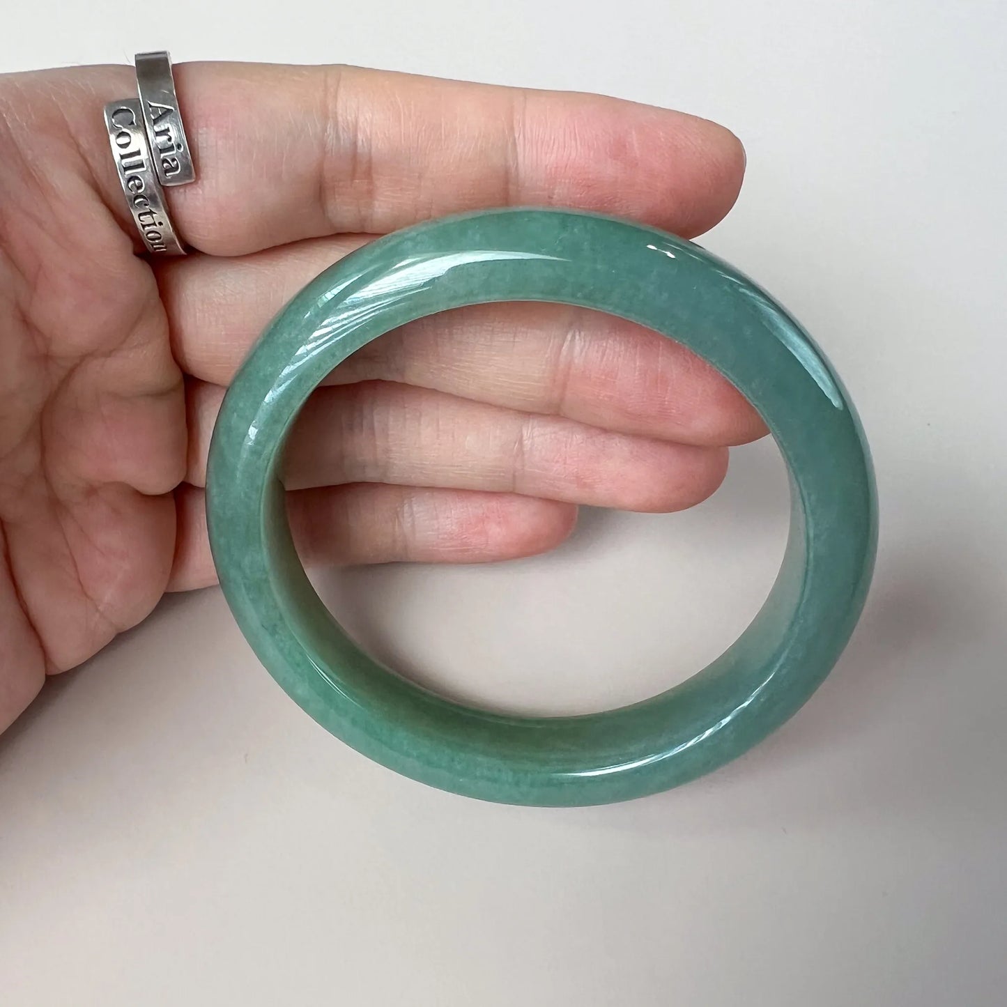 Handheld view of smooth green jade bangle showing polished finish and rounded profile