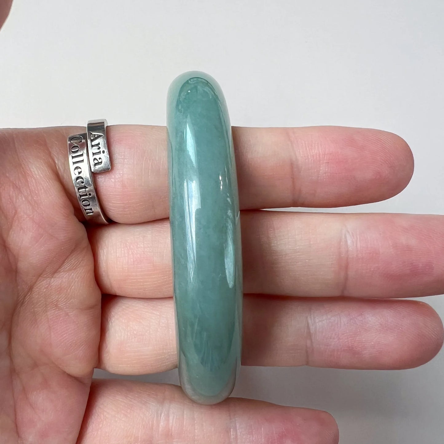Side profile of polished green jade bangle showing thickness and translucent finish