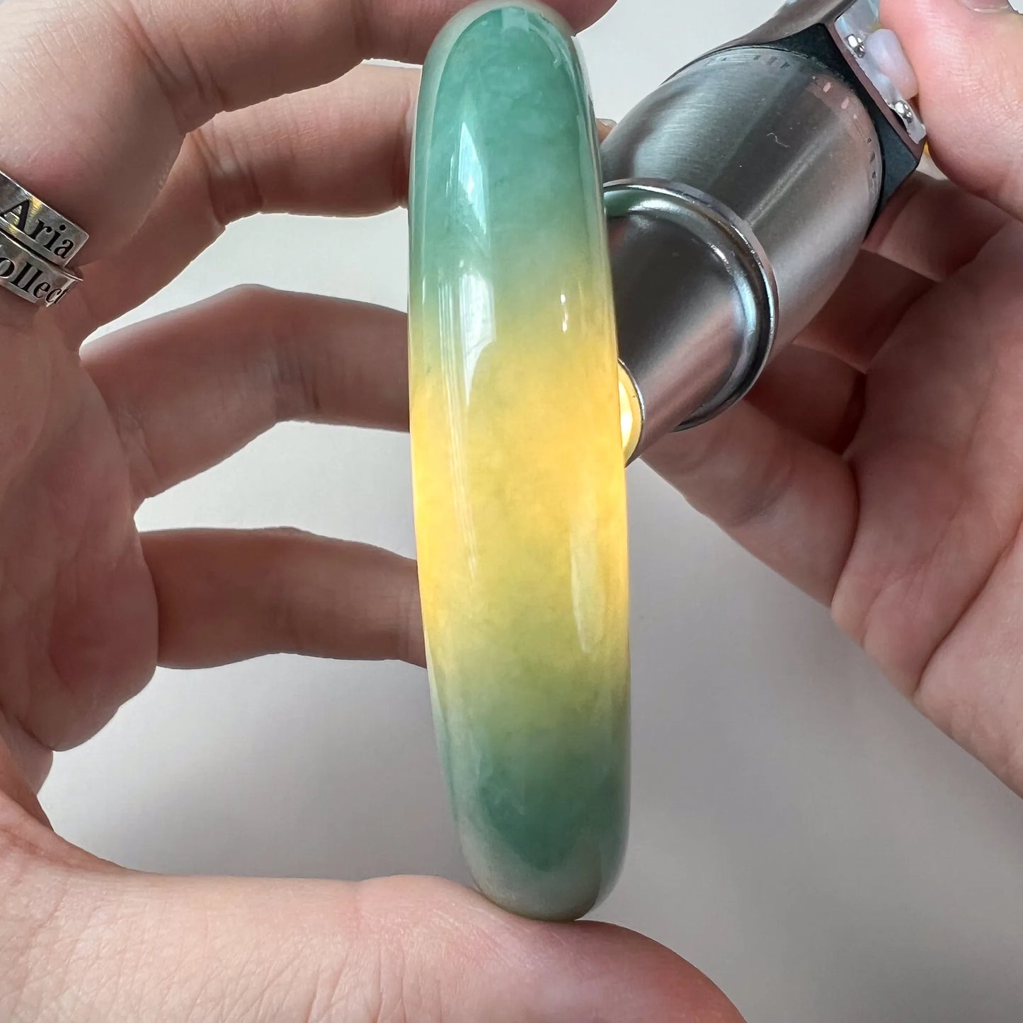 Side view of translucent jade bangle with green and yellow color grading under light