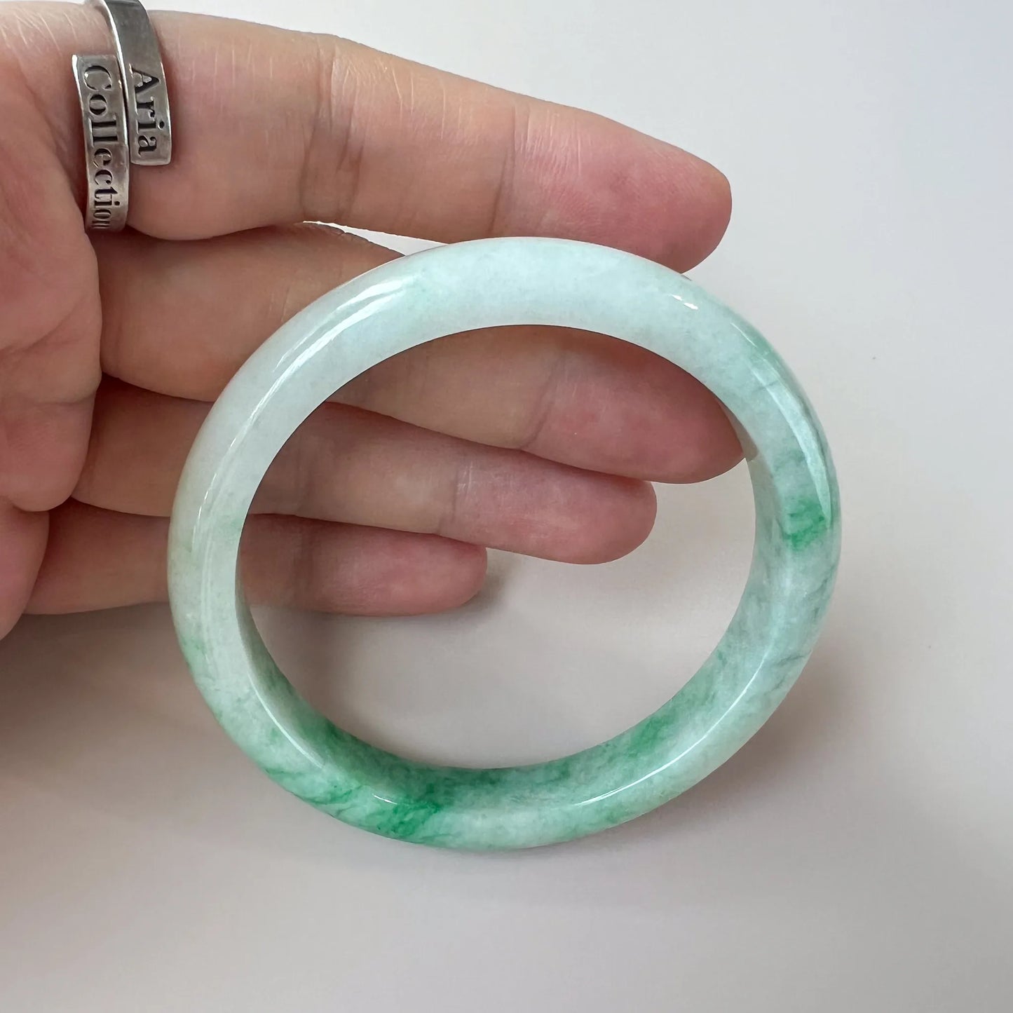 handheld view of pale green jade bangle with smooth glossy surface