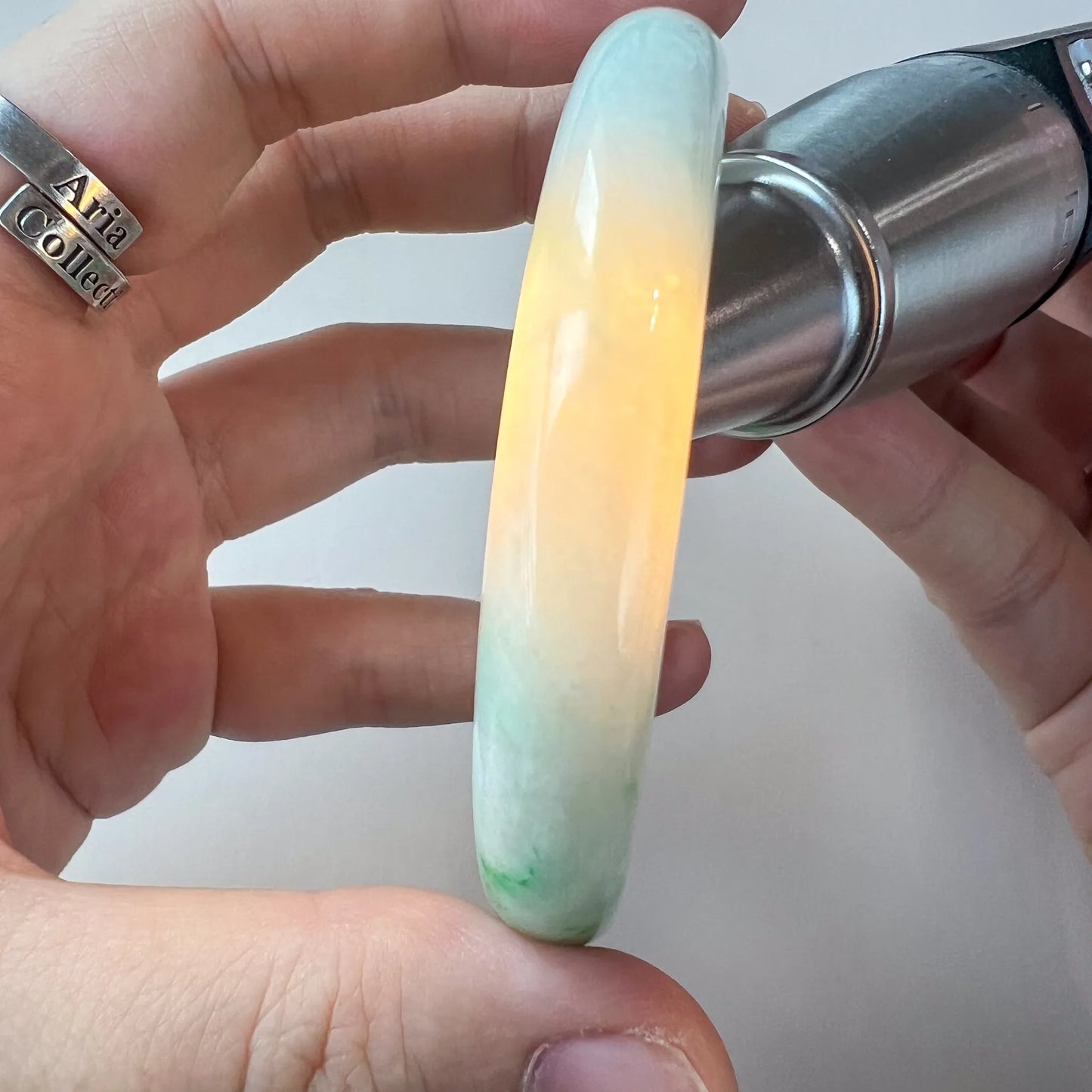 side view of pale jade bangle under light, showing creamy gradient and gloss