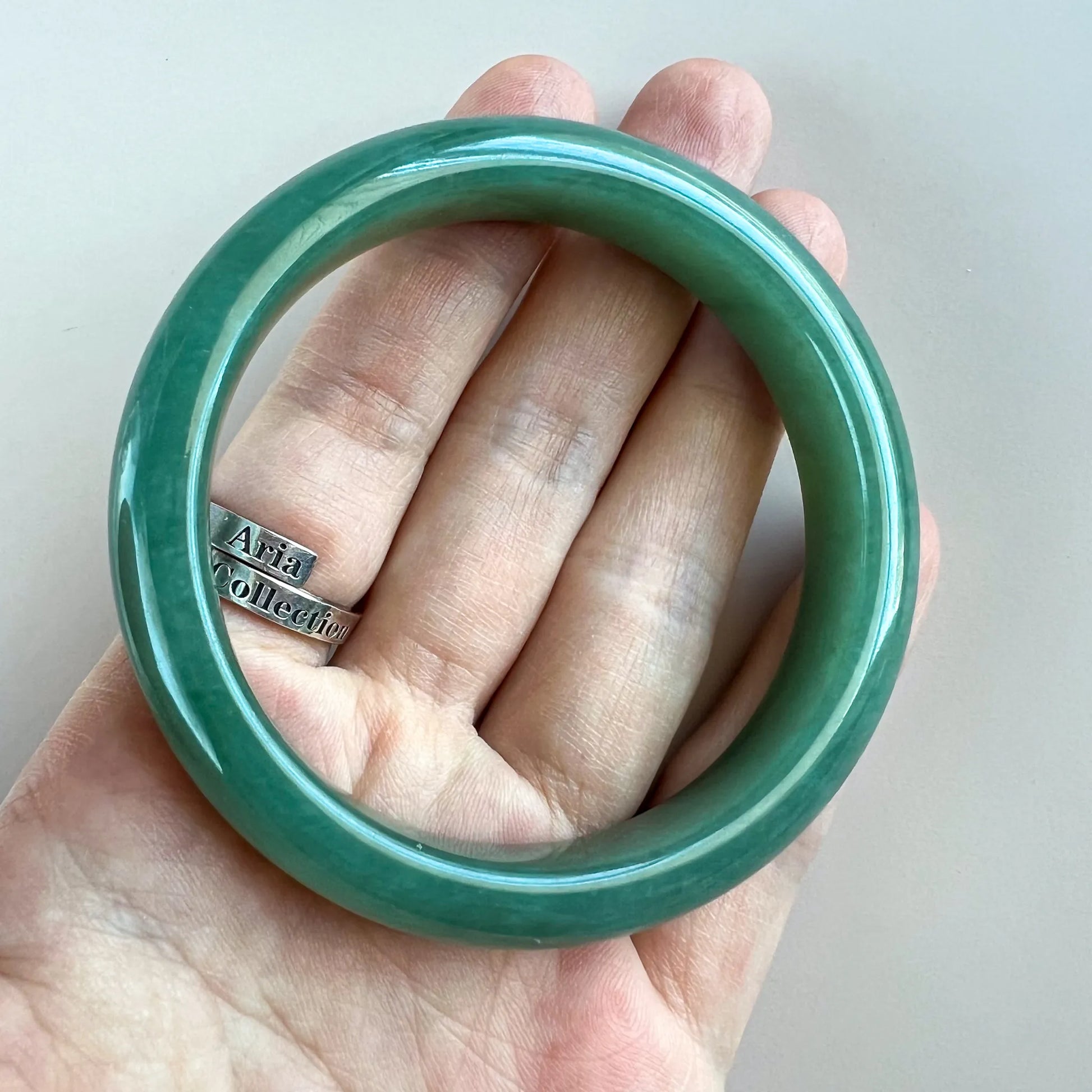 Green jade bangle shown on hand for scale, smooth glossy finish