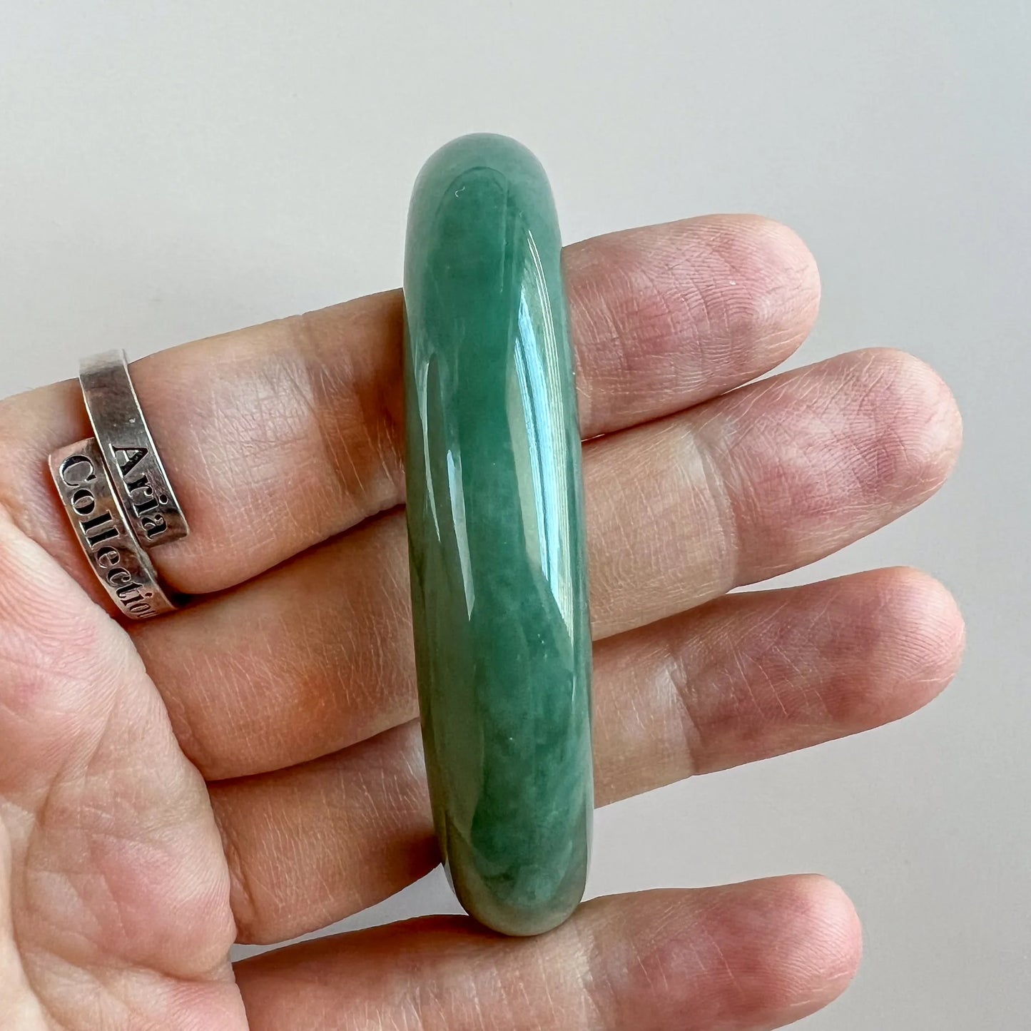 Side profile of thick green jade bangle on hand, polished stone finish