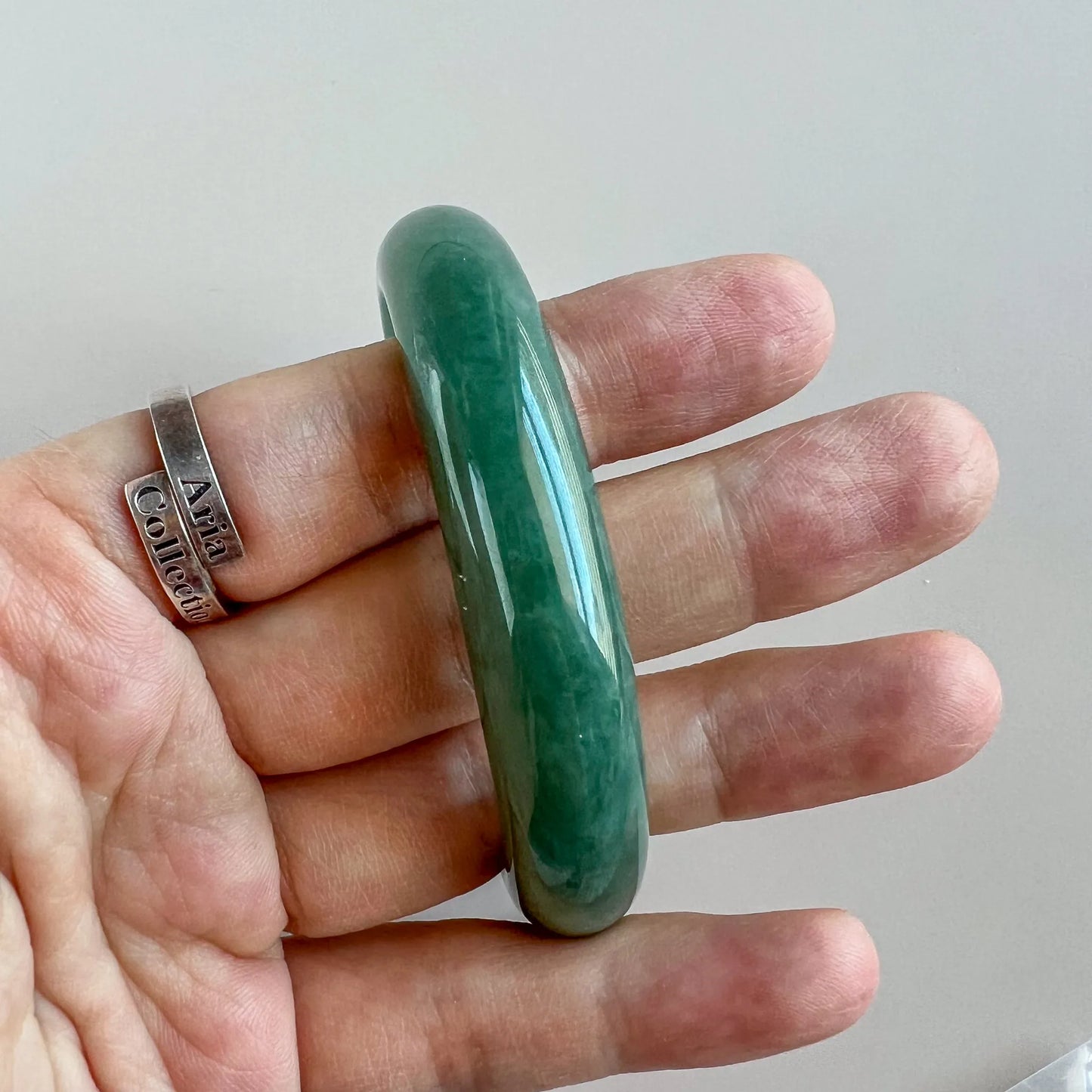Angled side view of green jade bangle on hand, smooth rounded edge