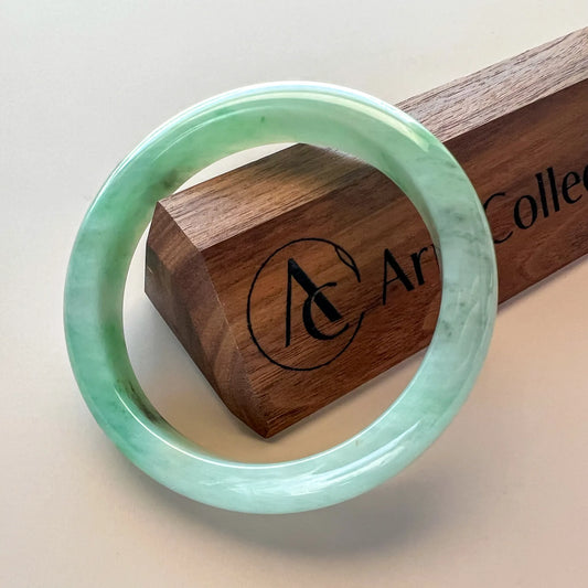 Glossy green jade bangle angled beside a branded wooden display box