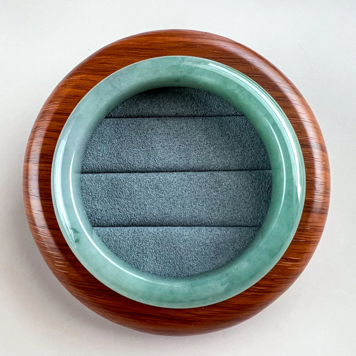 Top view of glossy green jade bangle resting on a wood display stand