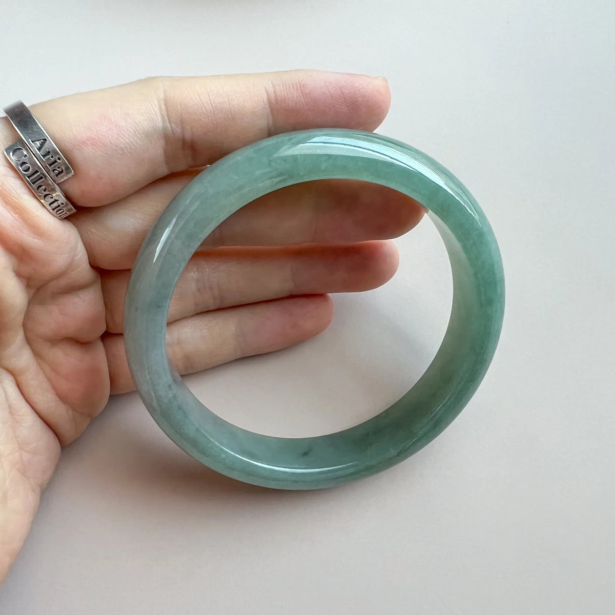 Close hand view of translucent green jade bangle with smooth polished surface