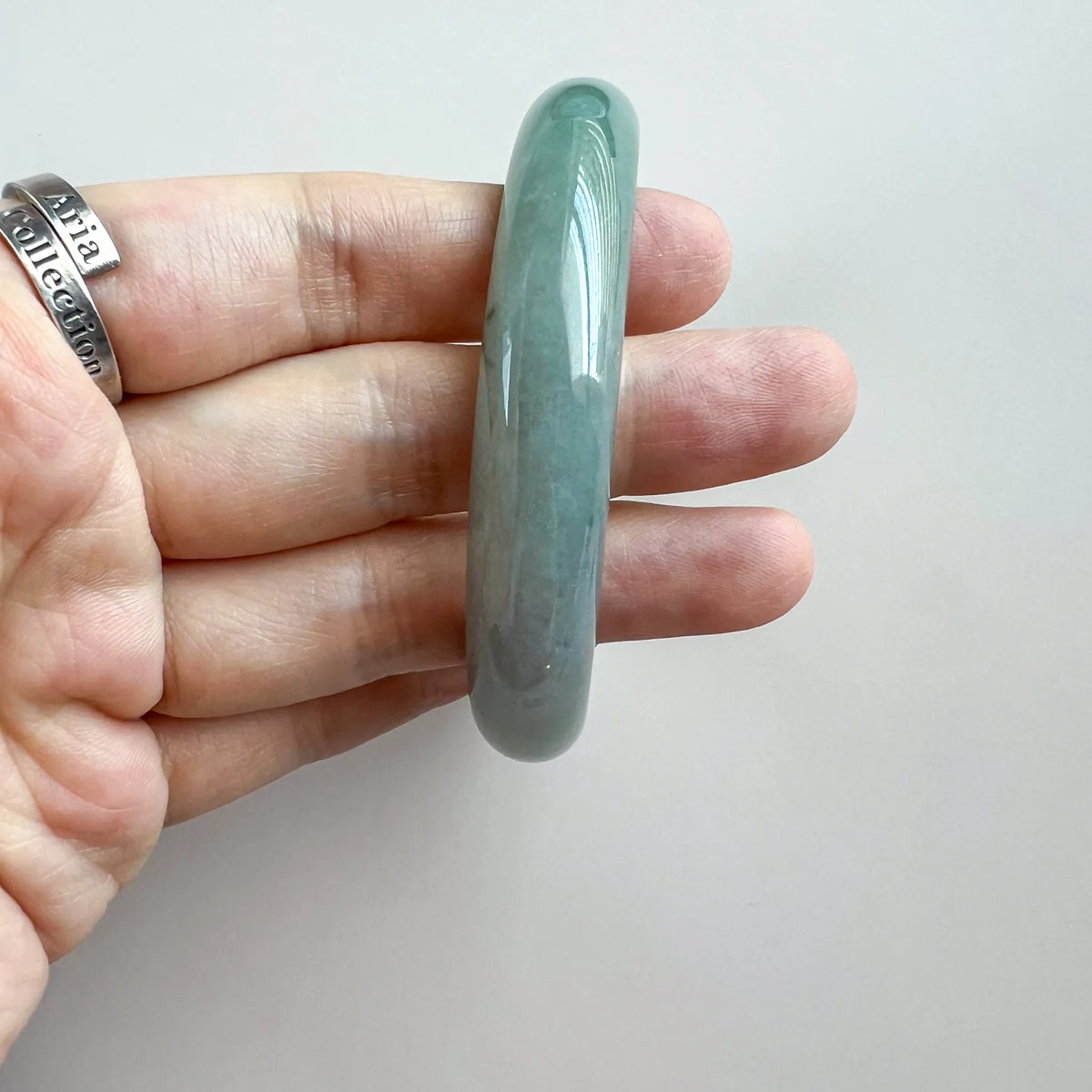 Side profile of rounded green jade bangle showing thickness and glossy polish