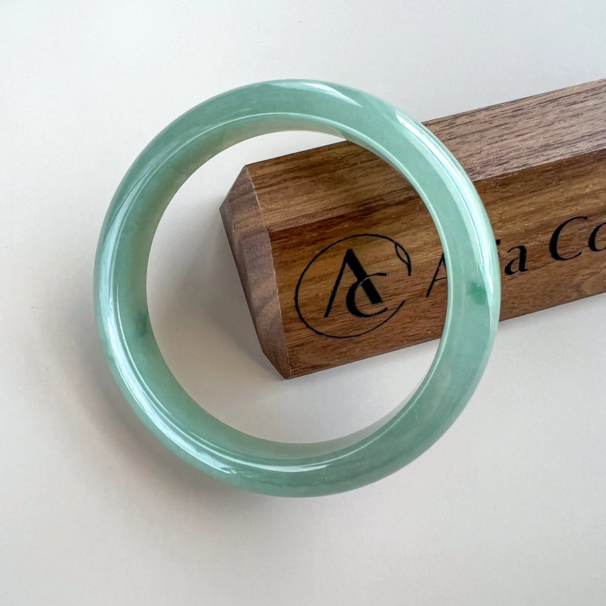 Front view of a smooth green jade bangle with glossy polished finish on white background