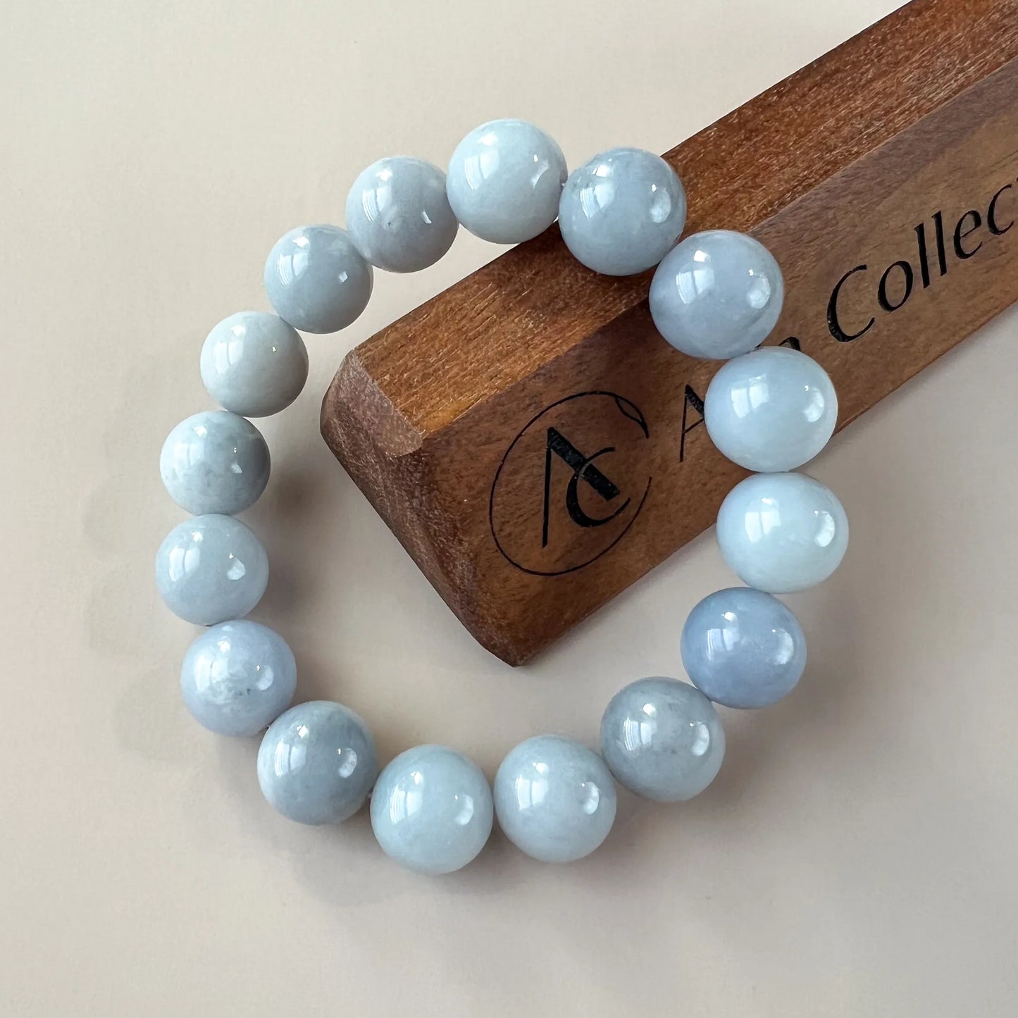 Round aquamarine bead bracelet shown on a branded wooden stand, glossy polished finish
