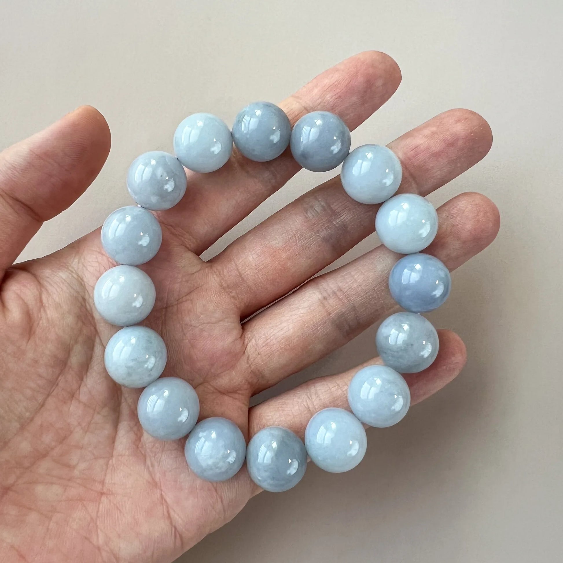 Pale blue stone bead bracelet worn on hand, polished round beads with smooth lustre