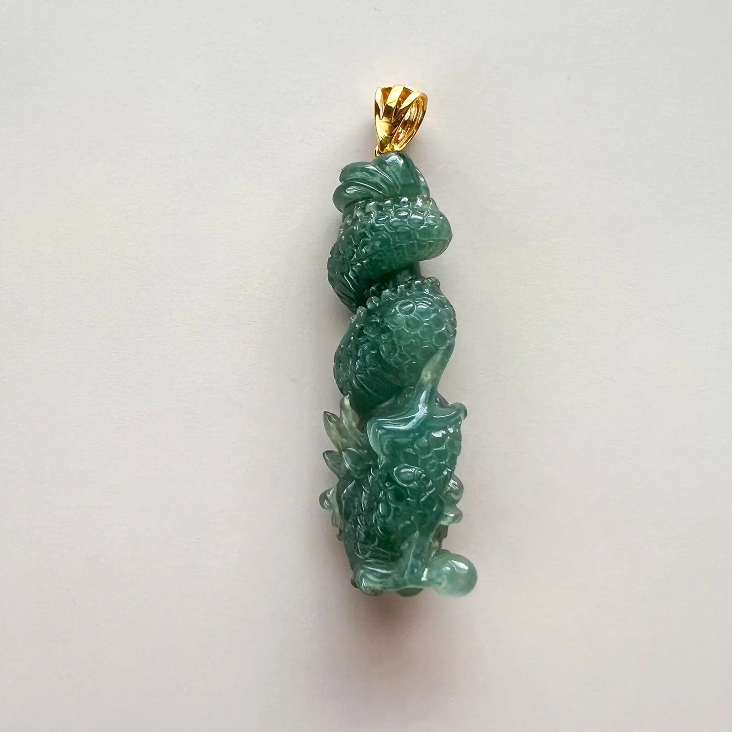 Back view of green natural jade dragon pillar pendant showing scale carving and sculpted gold-tone bail
