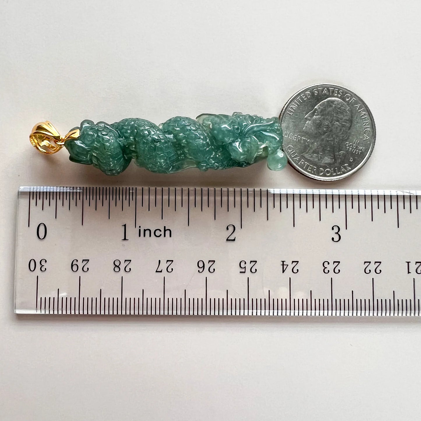 Side view with ruler and quarter showing carved green jade pendant size