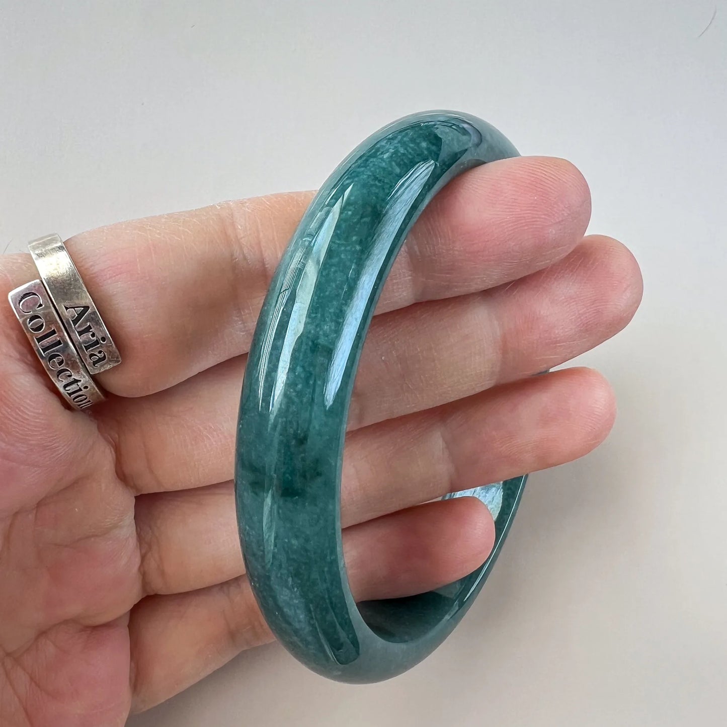 Angled side view of a green jade bangle with smooth glossy finish