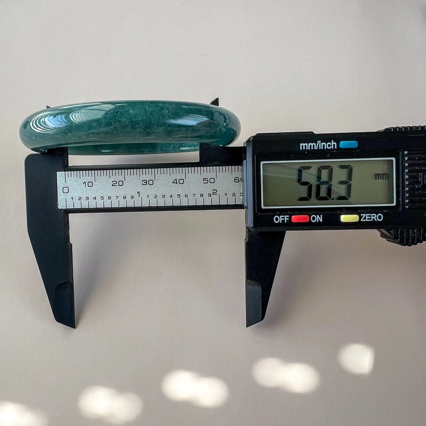 Side profile of green natural jade bangle measured at 58.3 mm with caliper