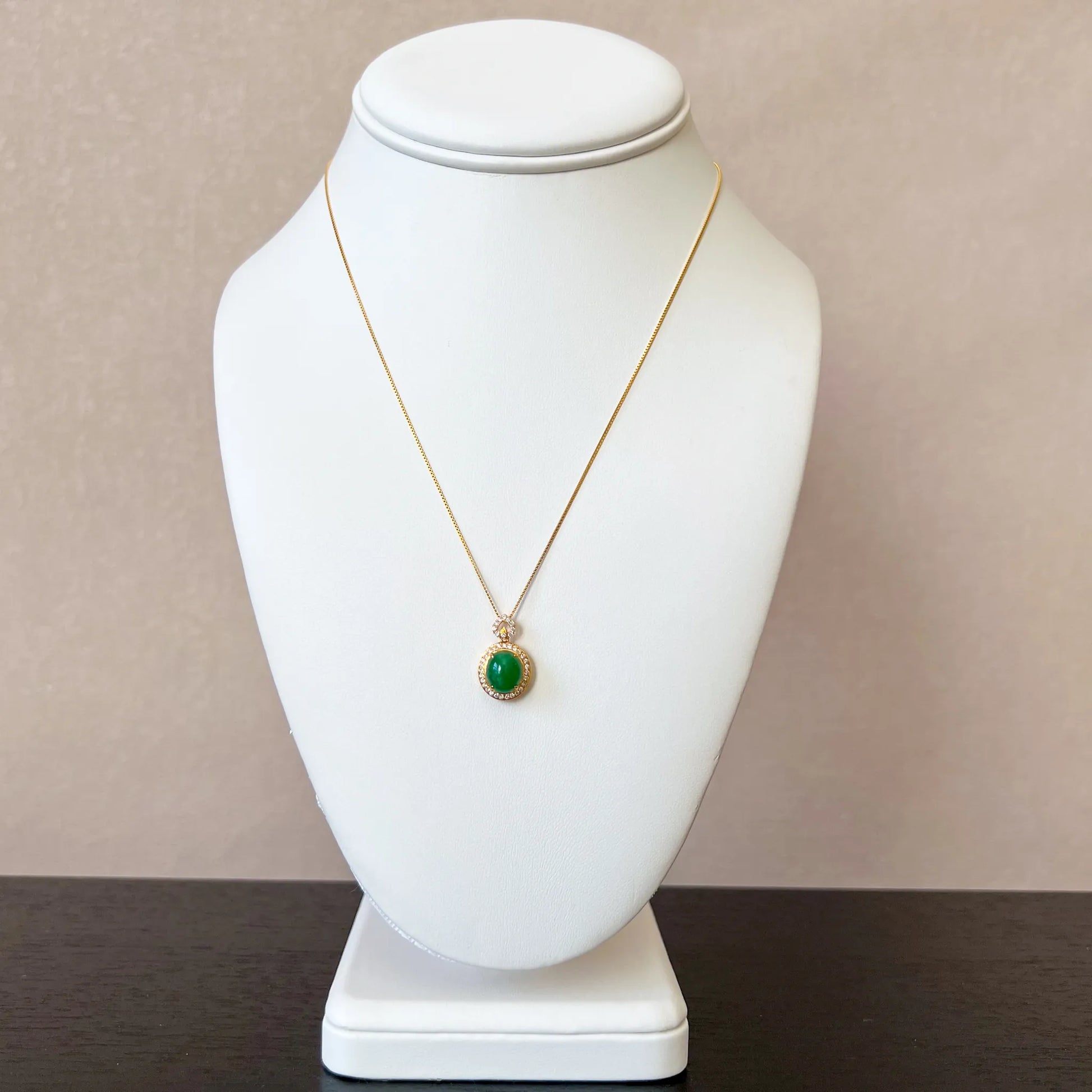 Aria Collection green natural jade oval cabochon pendant in polished gold-tone setting on necklace bust