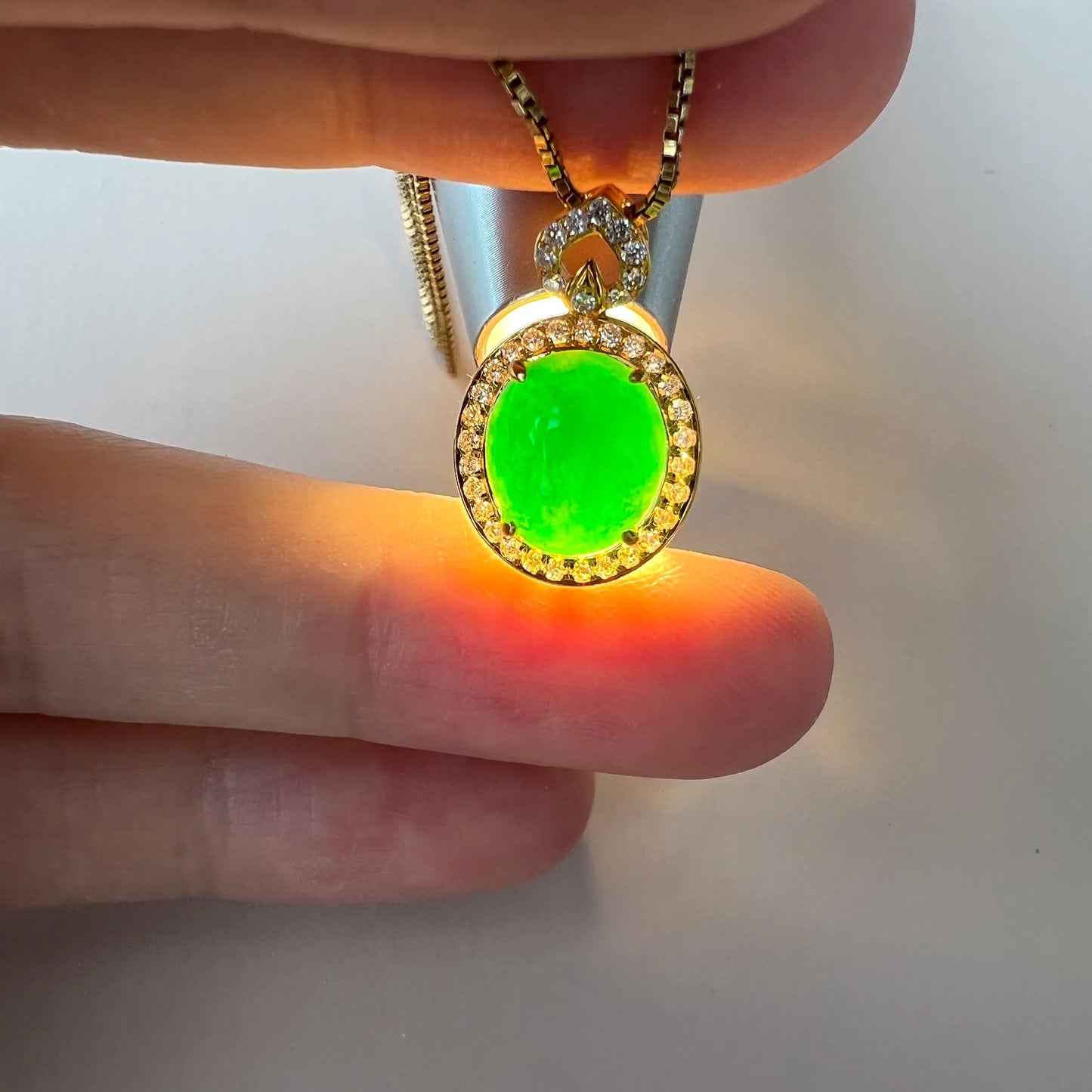 Pendant glowing under backlight, showcasing translucent green gemstone and diamond halo