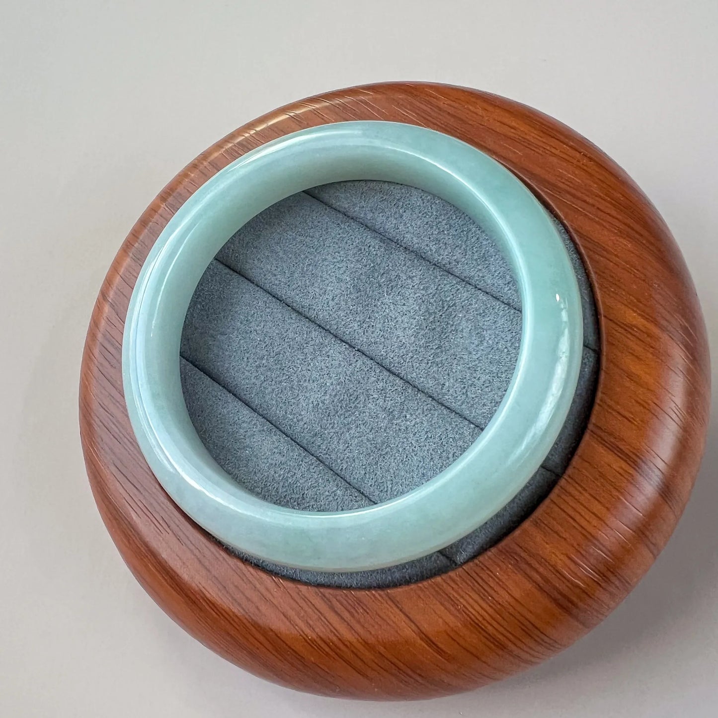 Top view of polished jade bangle resting on a wood and gray display base