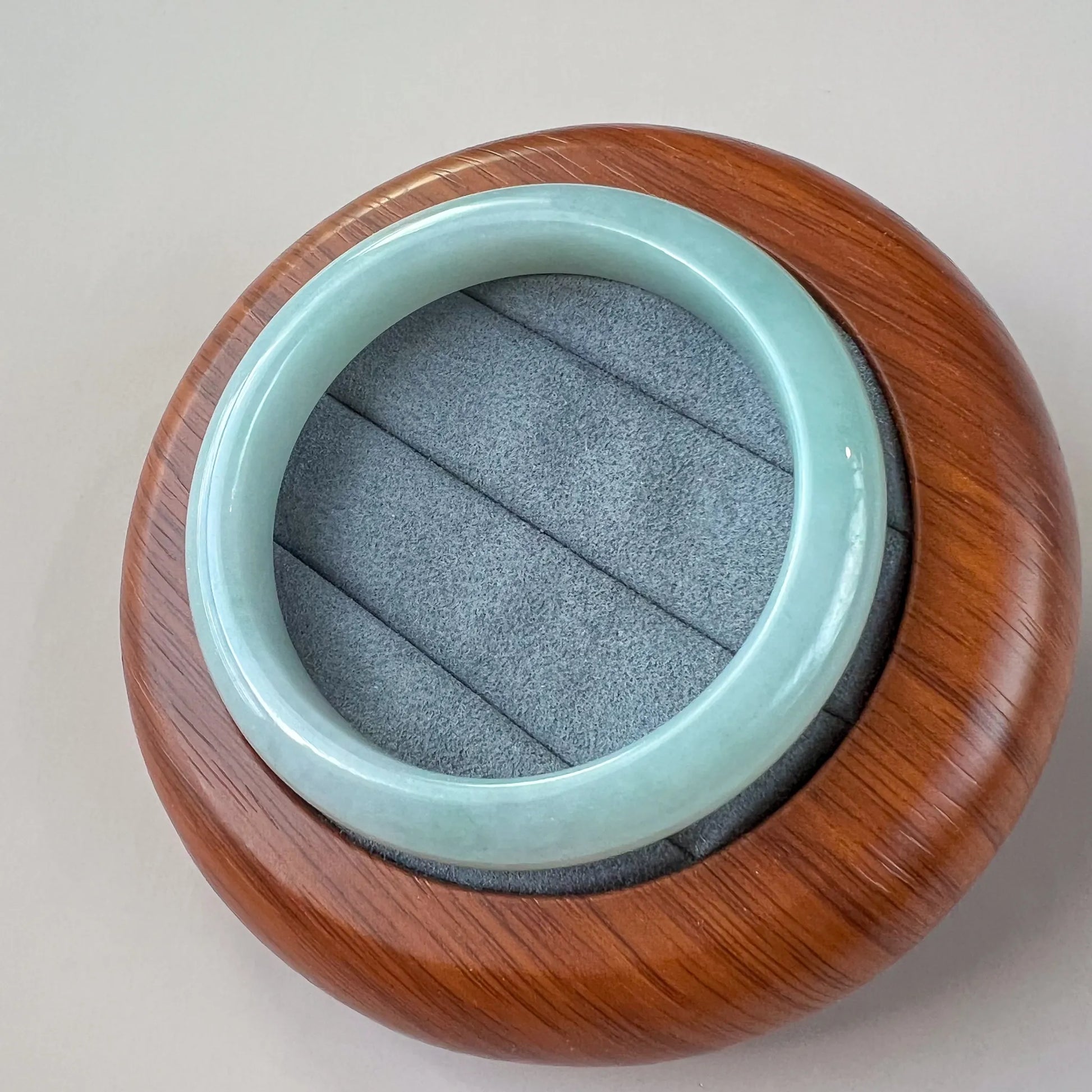 Top view of polished jade bangle resting on a wood and gray display base