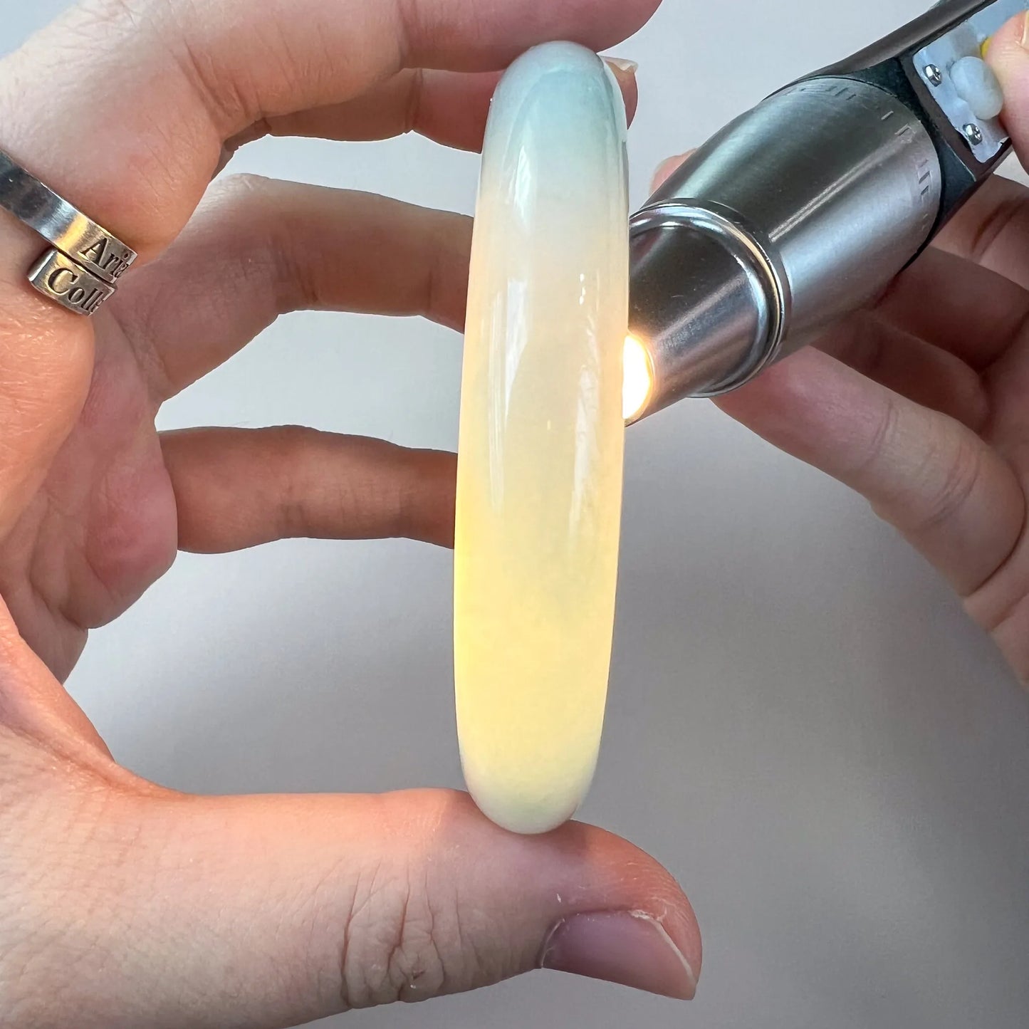 Translucent jade bangle lit from behind to show creamy yellow glow