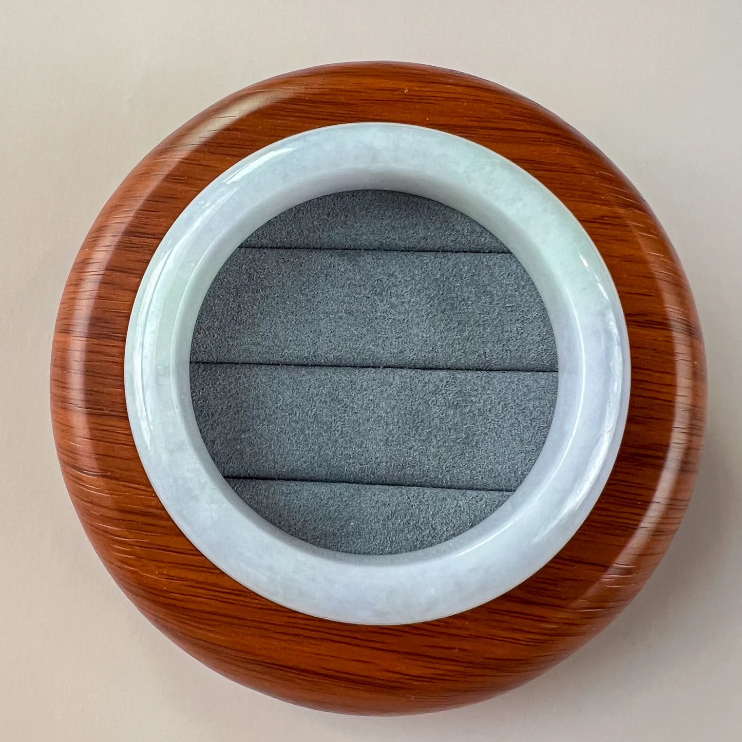 Top view of pale blue jade bangle in wooden display base, polished round profile