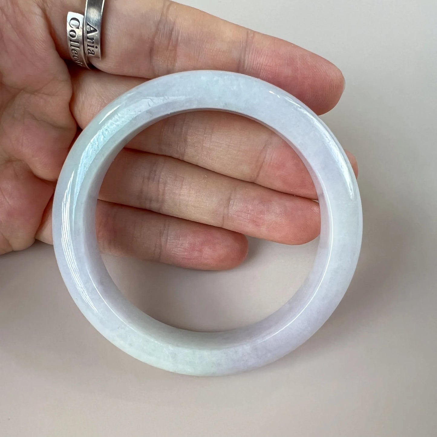 Close view of icy white natural jade bangle showing inner curve, rounded thickness, and polished surface