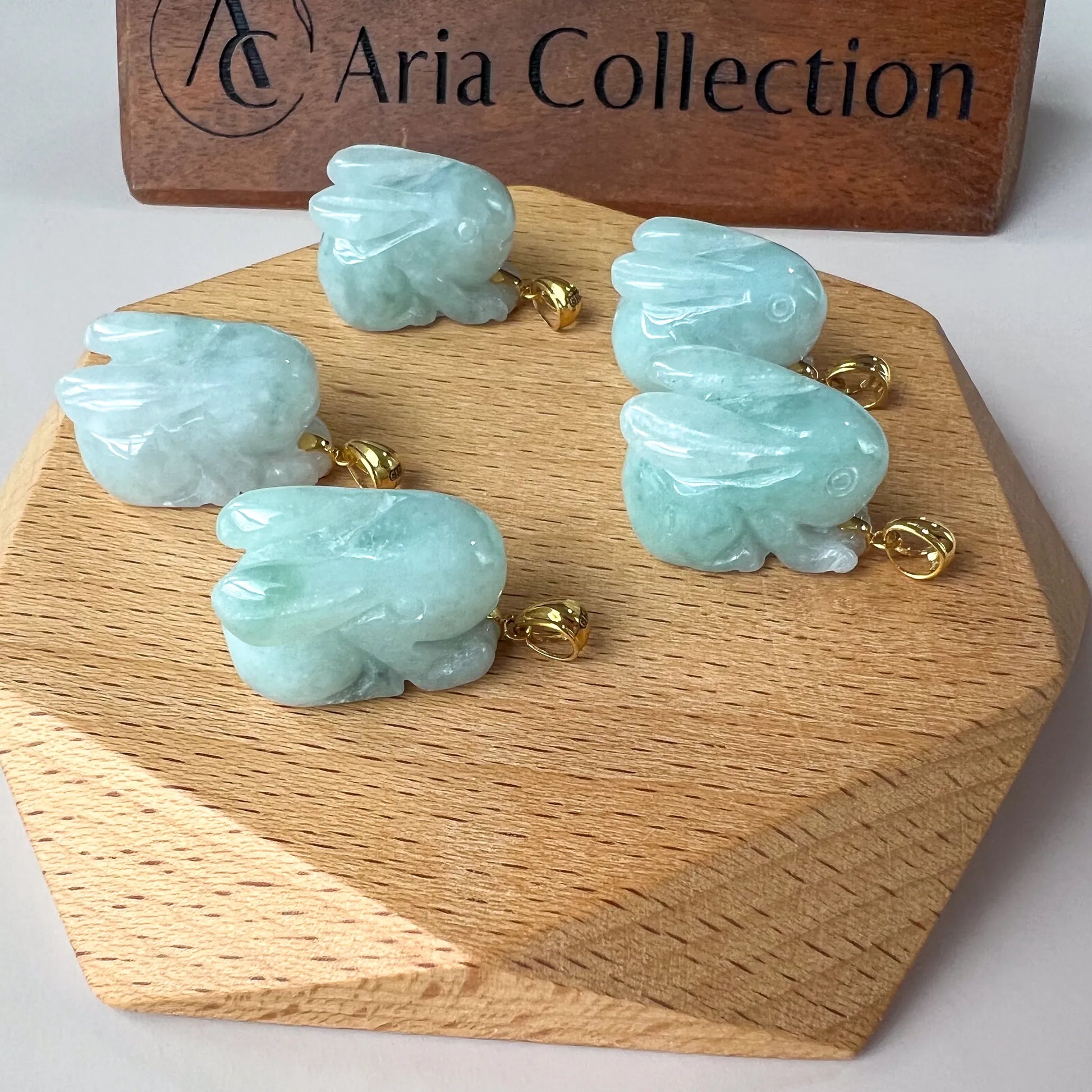 Angled view of carved aqua jade bunny pendant with glossy finish and gold bail
