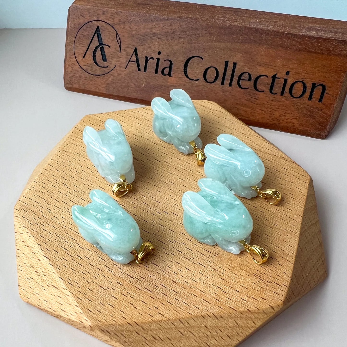 Side angle of translucent blue jade rabbit pendants showing carved ears and gold hardware