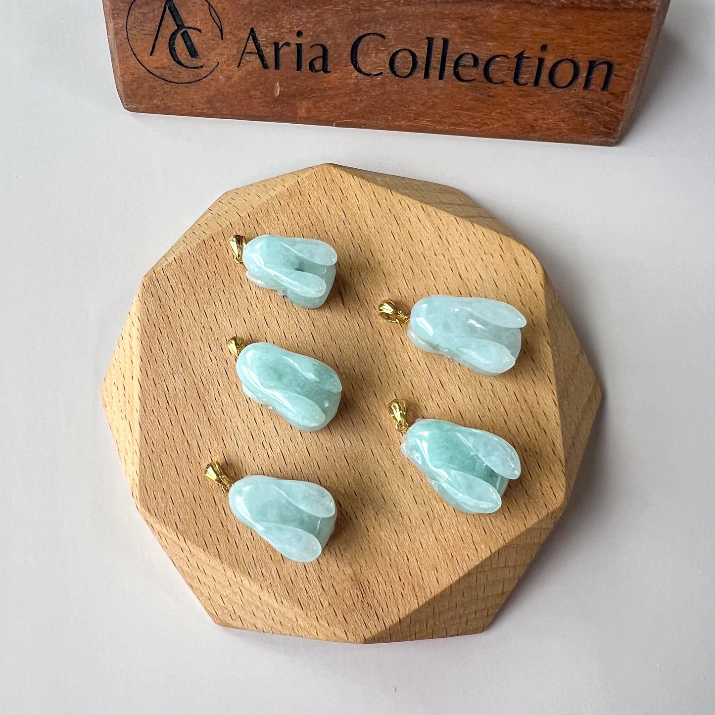 Overhead view of small aqua jade bunny pendants arranged on a faceted wood tray