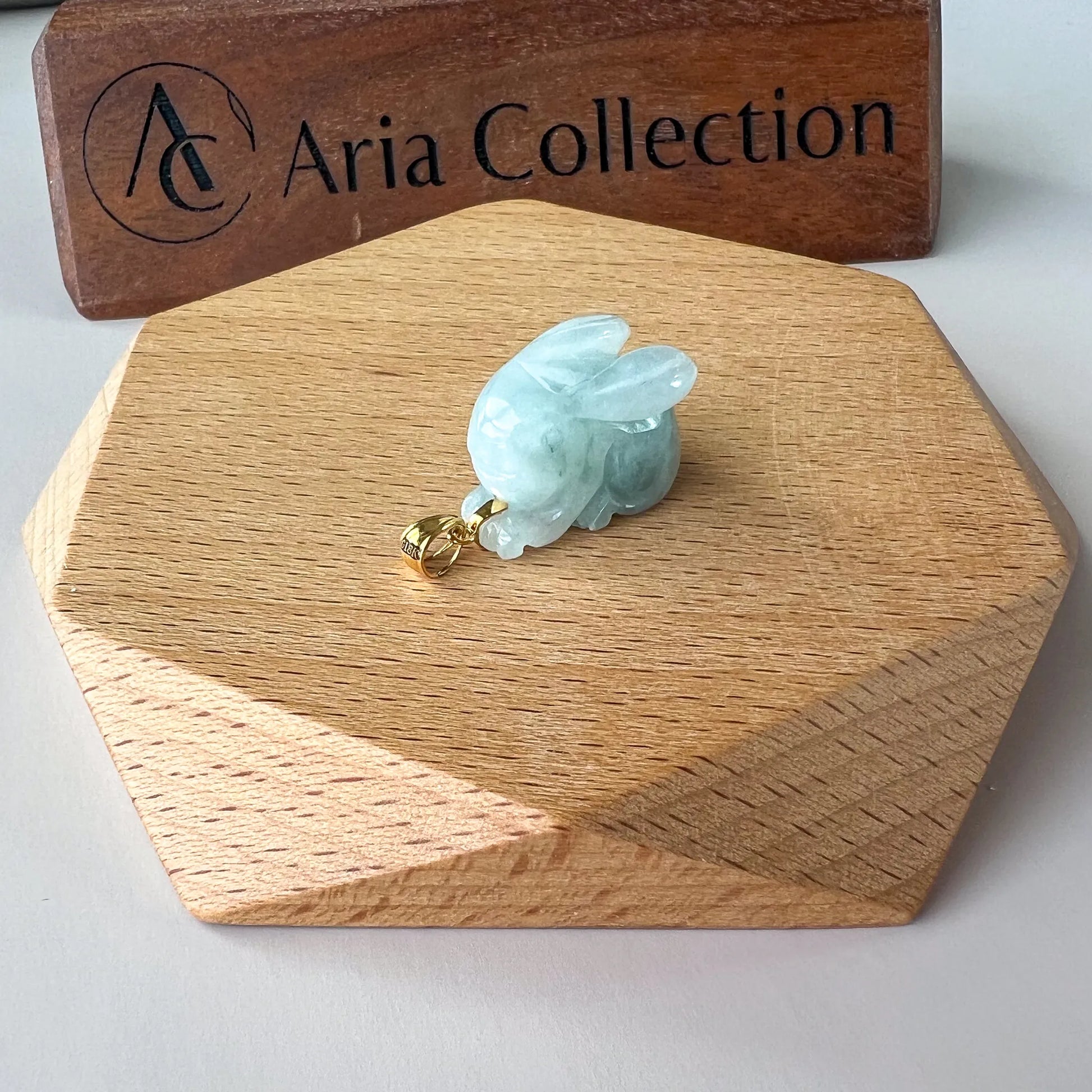 Side view of pale aqua green rabbit pendant showing rounded carving and gold-toned bail