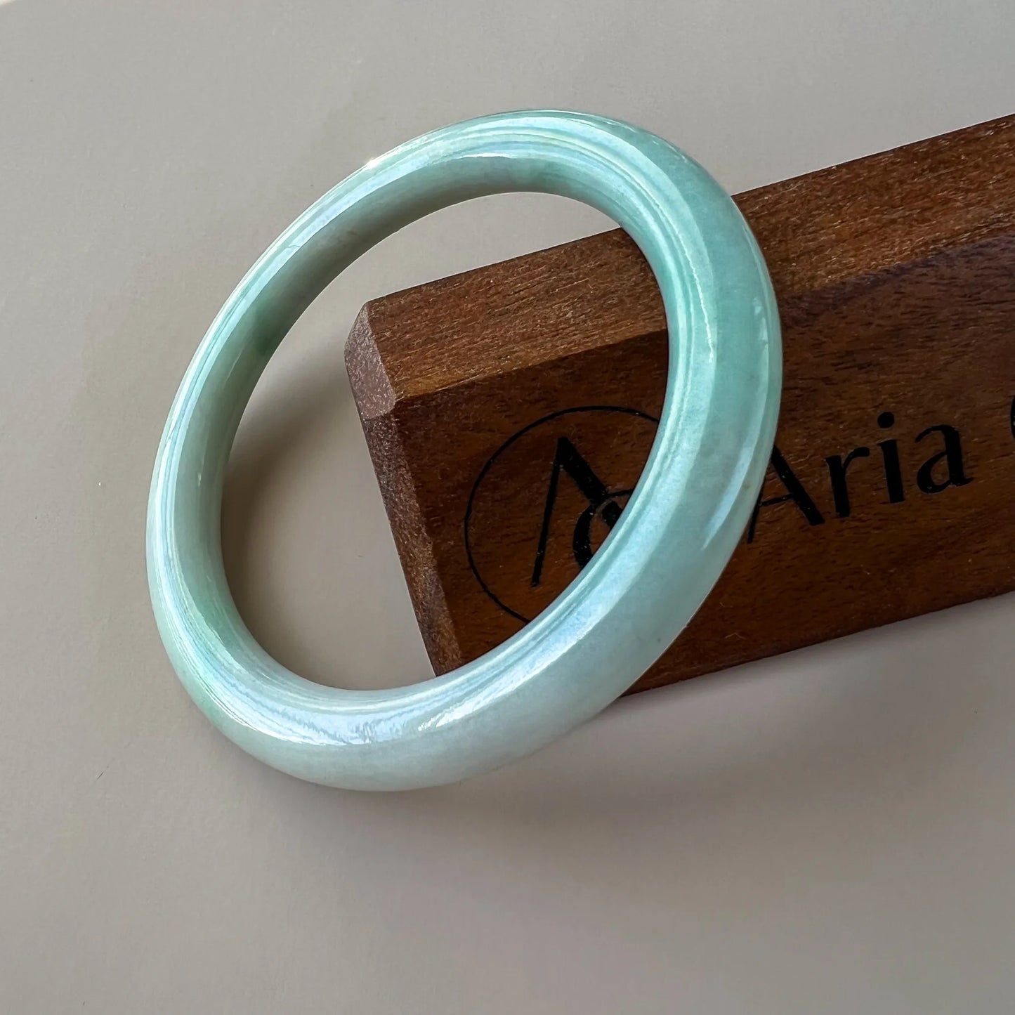 Glossy light green jade bangle with smooth rounded profile on display