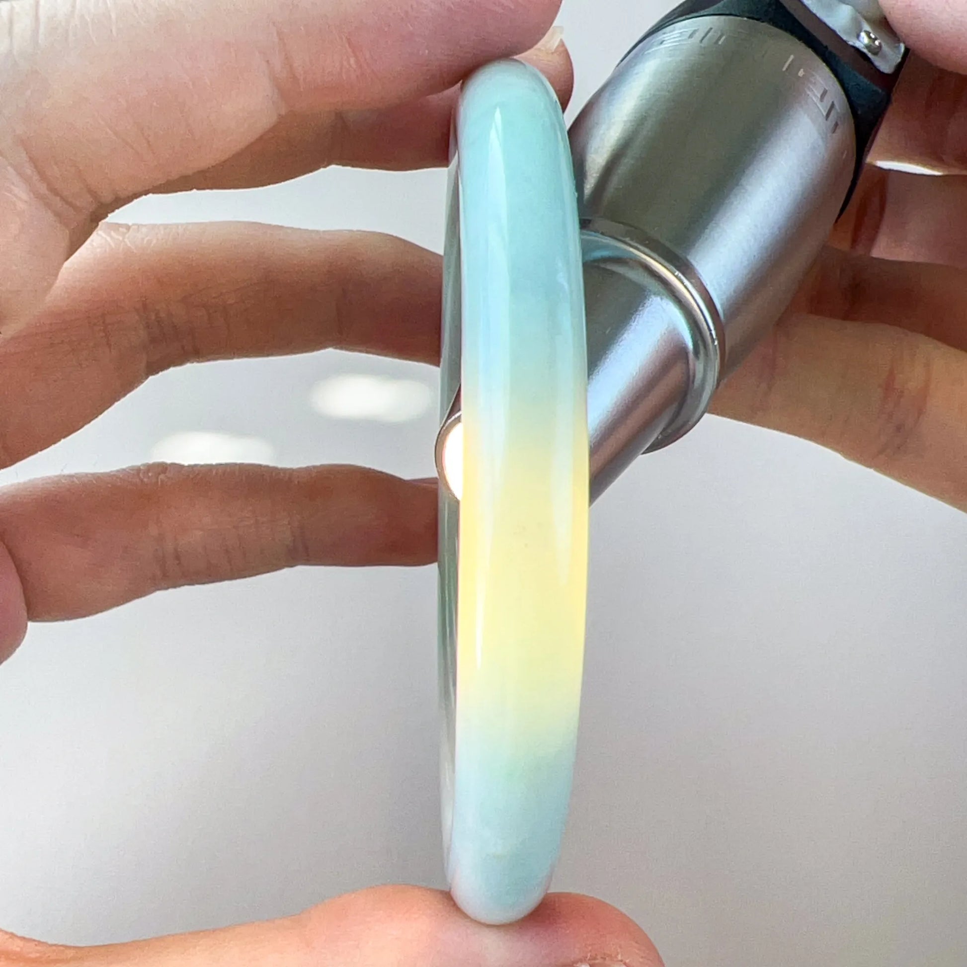 Side view of translucent light blue-green jade bangle lit from behind