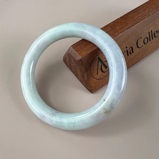 Glossy pale blue jade bangle with smooth round profile on a wooden display block