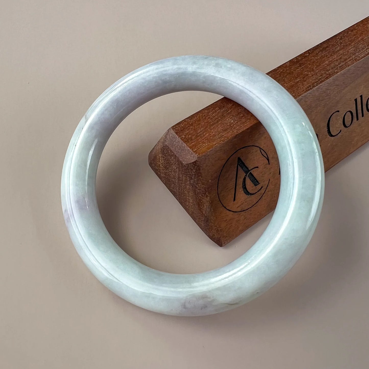 Front view of polished light blue jade bangle with subtle mottled texture on neutral background