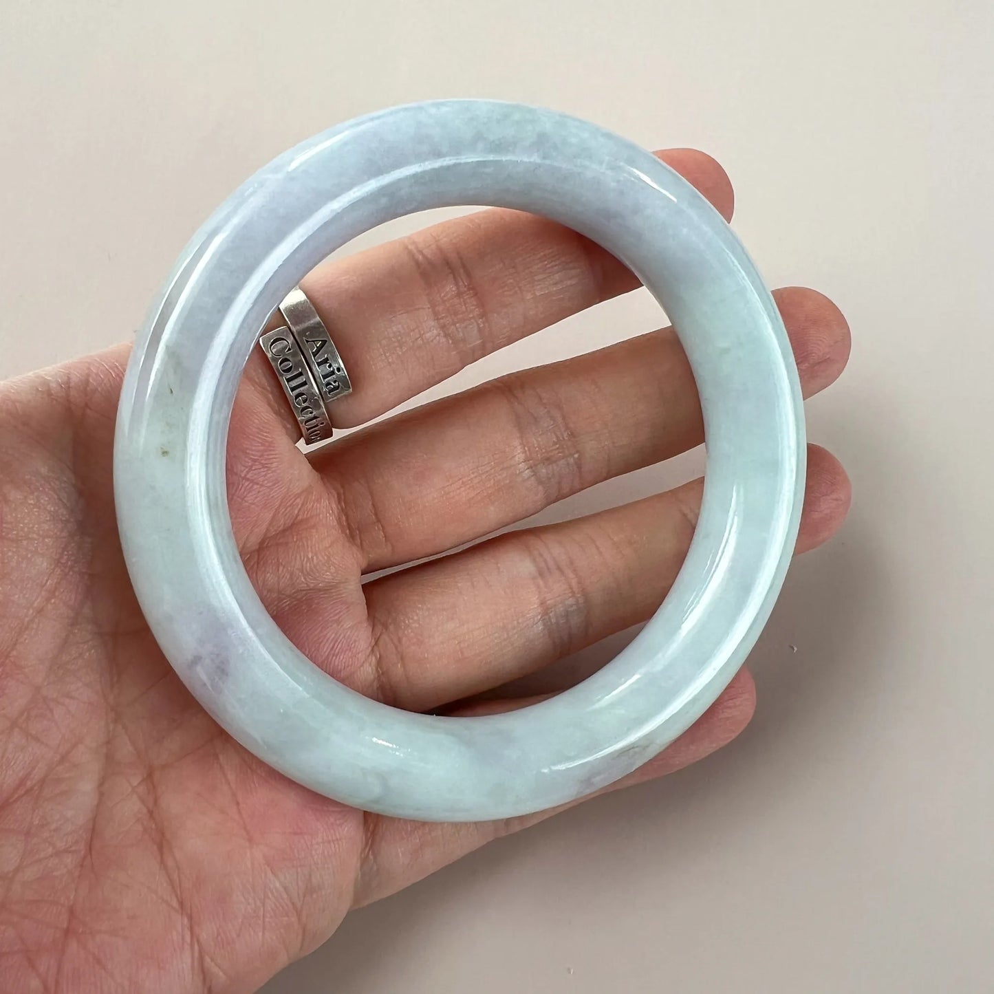Handheld view of glossy light blue jade bangle with rounded thick band